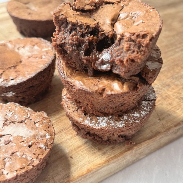 a stack of brownie bites on a wooden chopping board