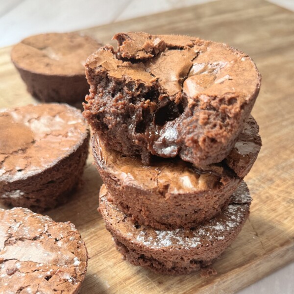 a stack of brownie bites on a wooden chopping board