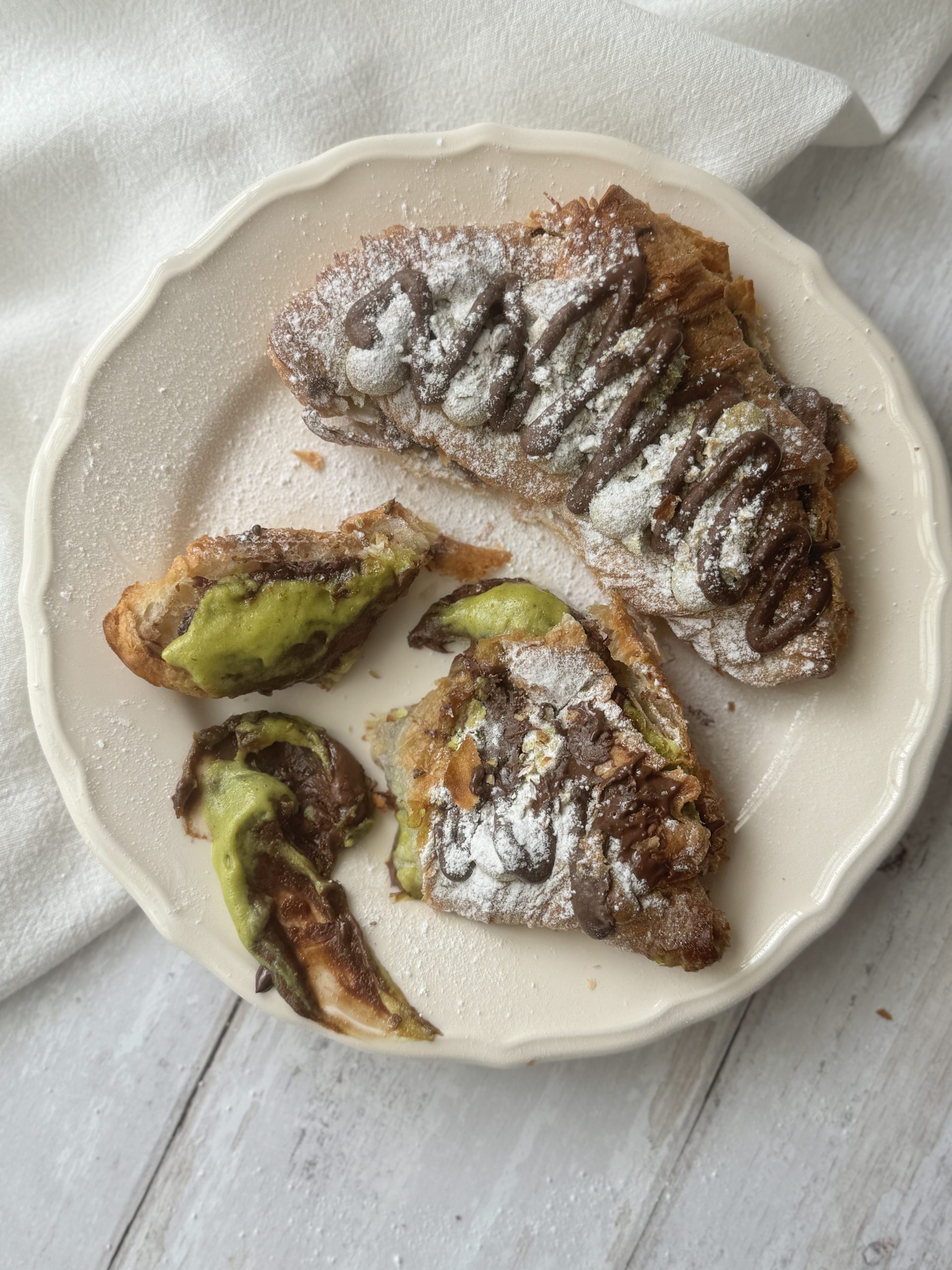 2 pistachio croissants on a white plate