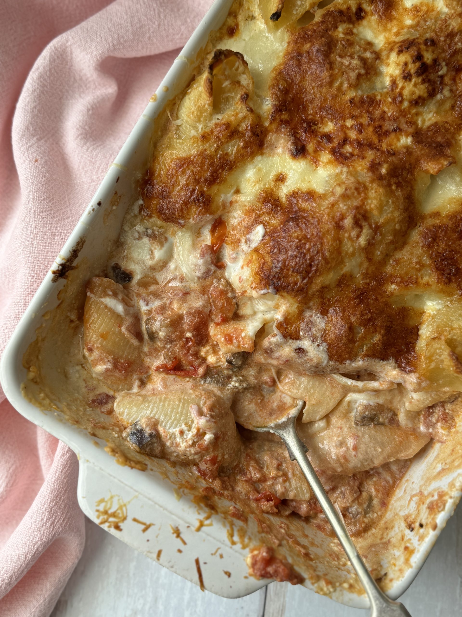 aubergine pasta with giant shells in a baking dish with a spoon