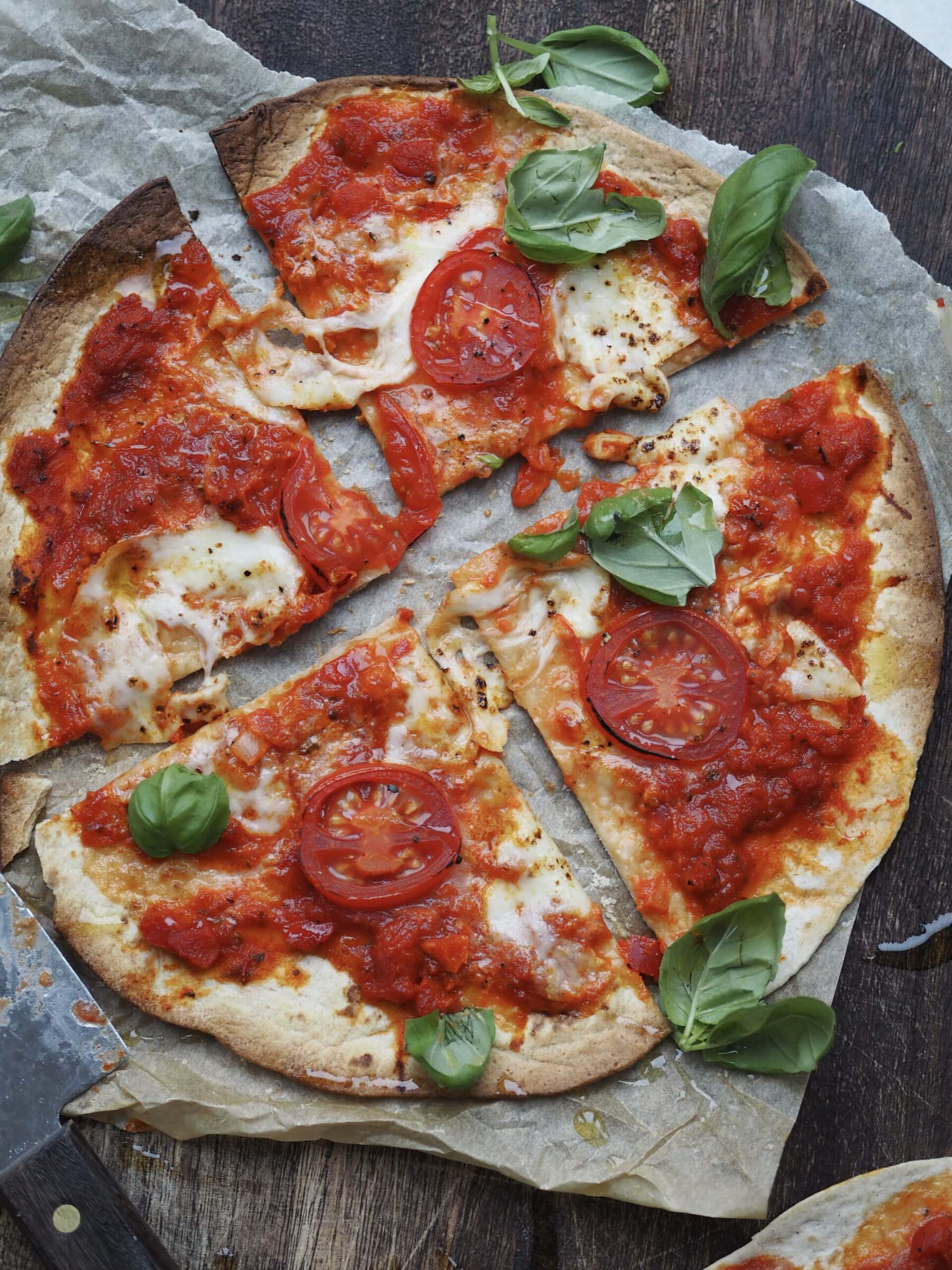 flatbread margherita pizza on a board cut into four.