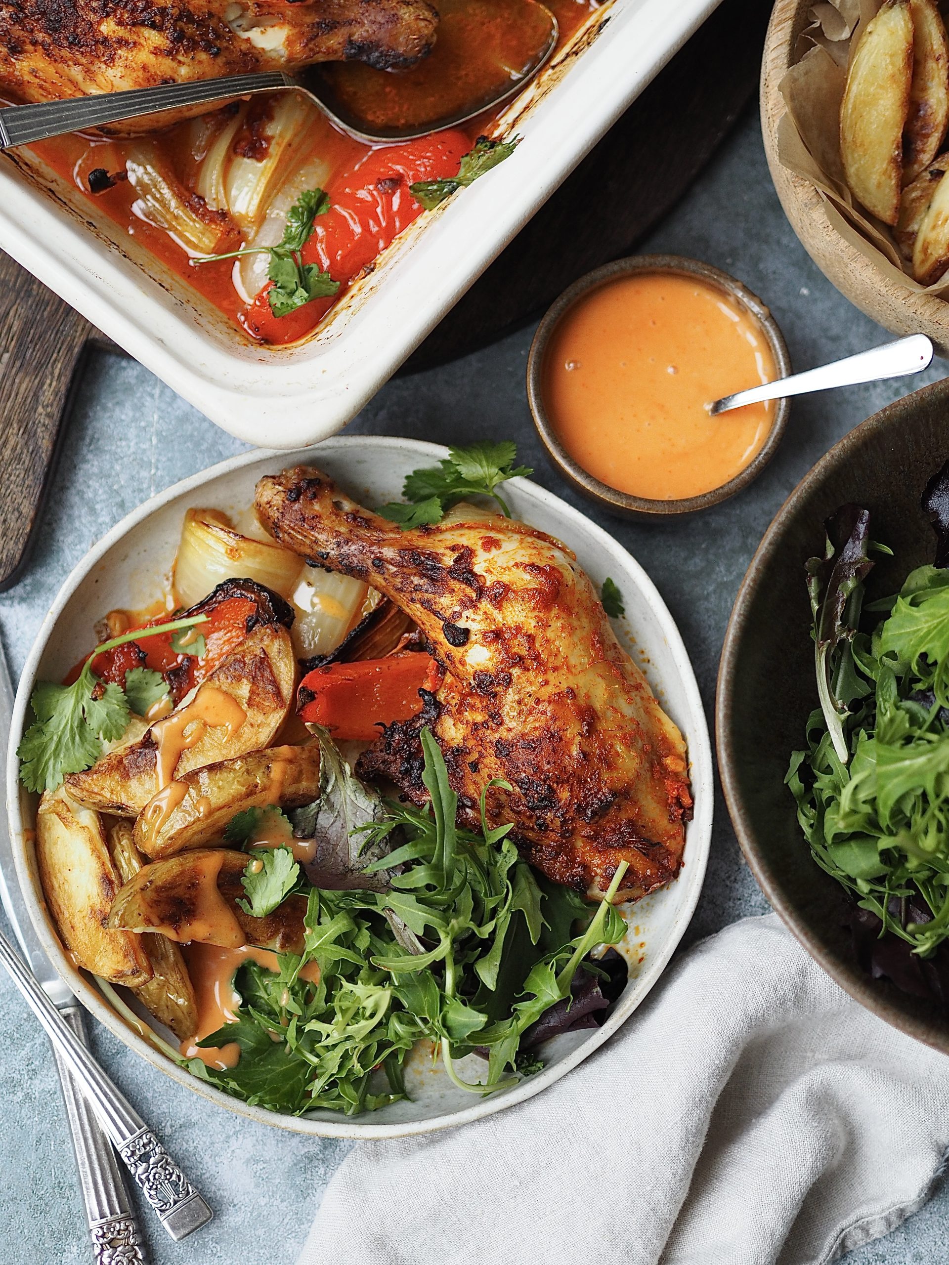 Plated peri peri chicken legs with potato wedges and salad.