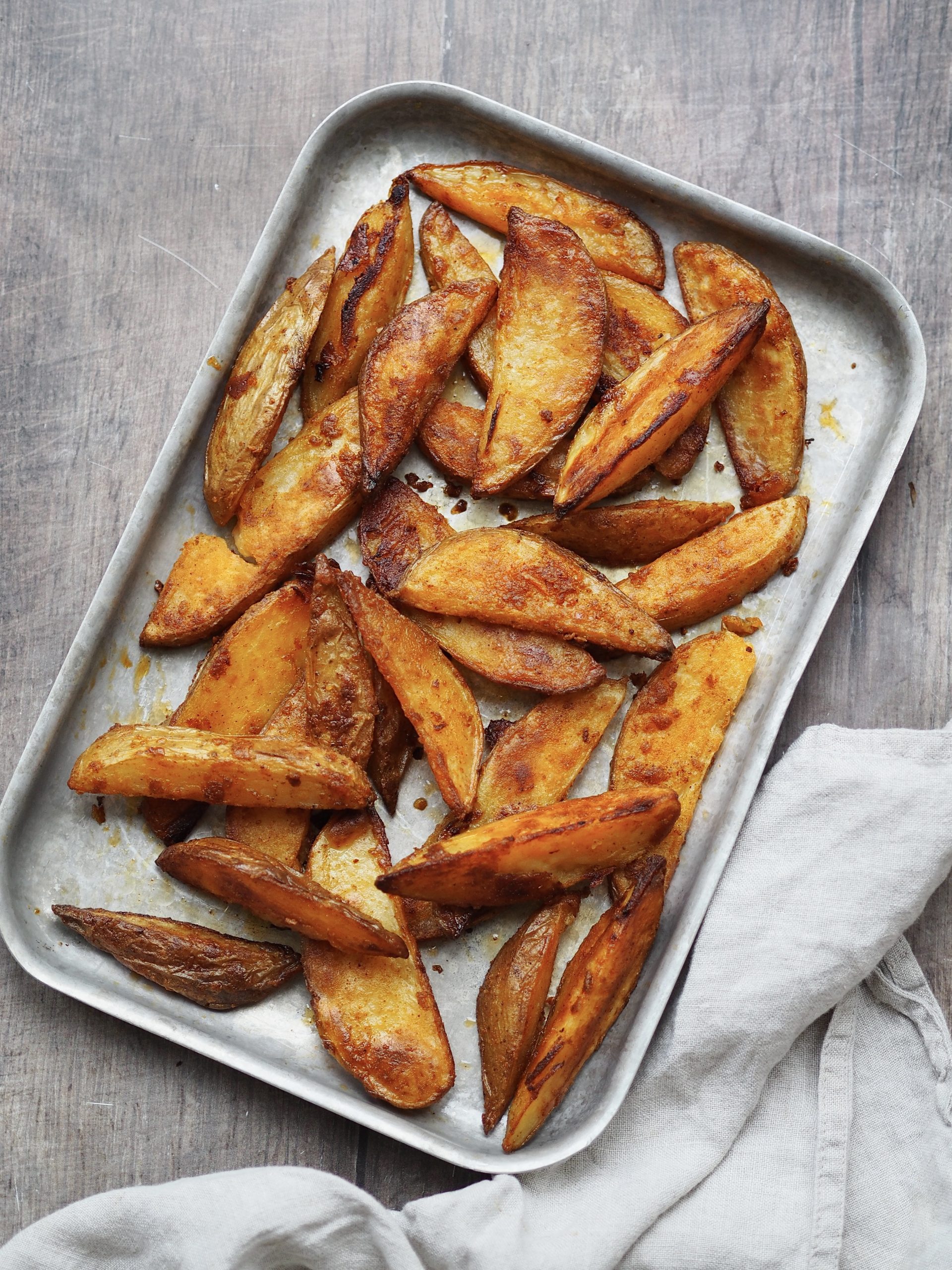 Tray of potato wedges on a grey background.