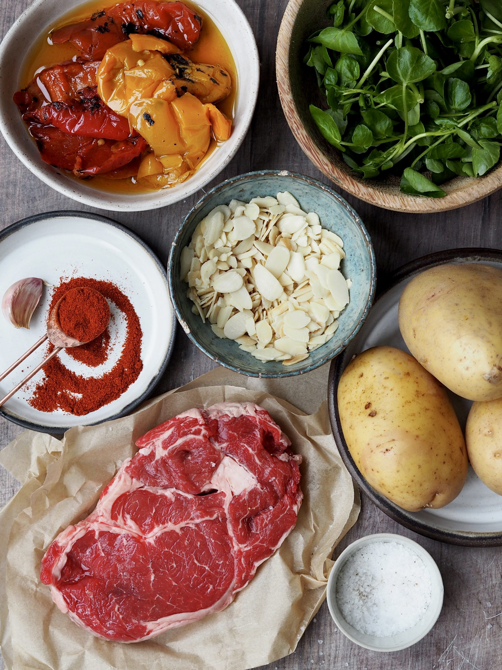 Ingredients to make rib eye steak with potato wedges, romesco sauce and watercress.