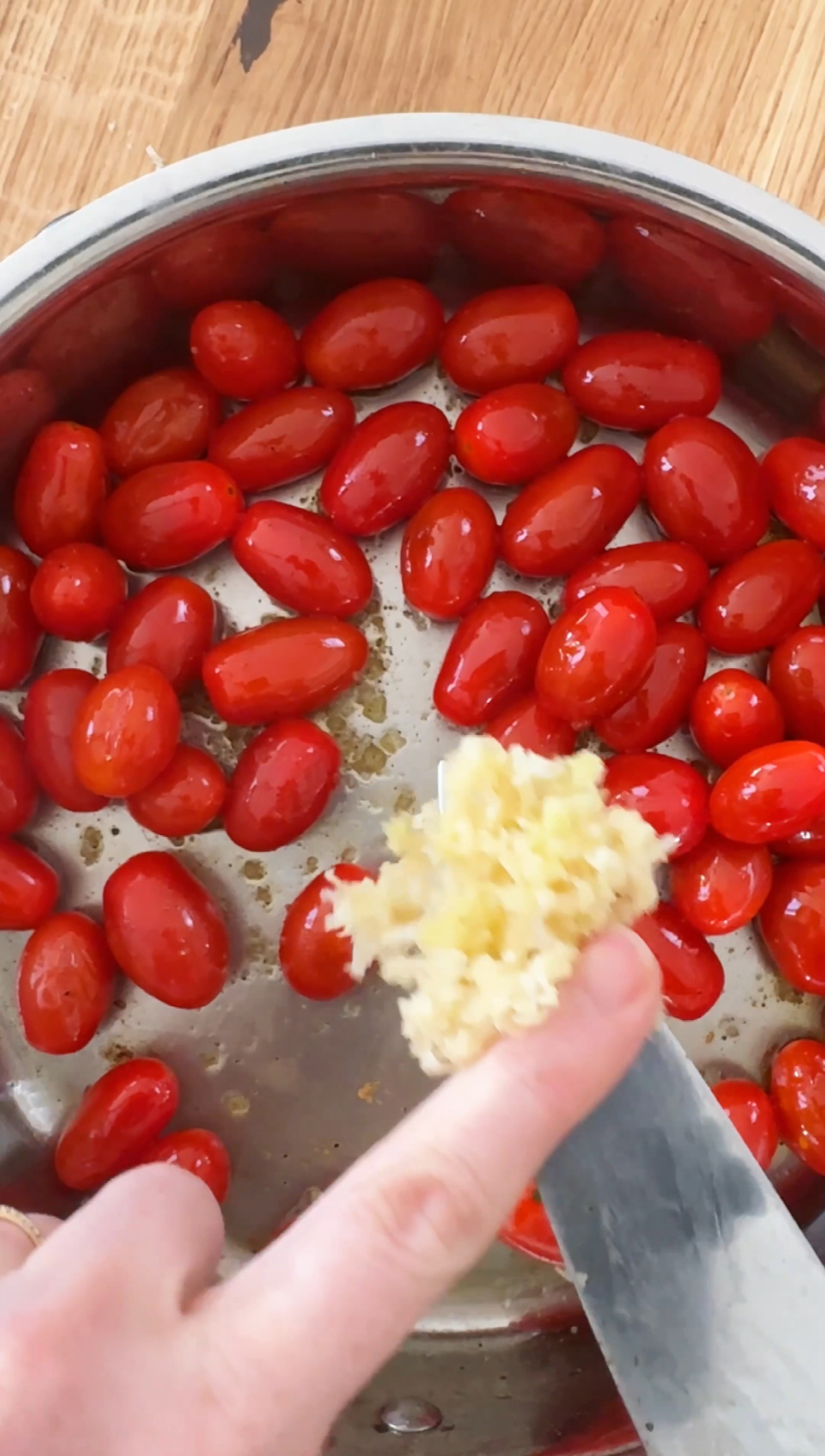 adding garlic to cherry tomatoes