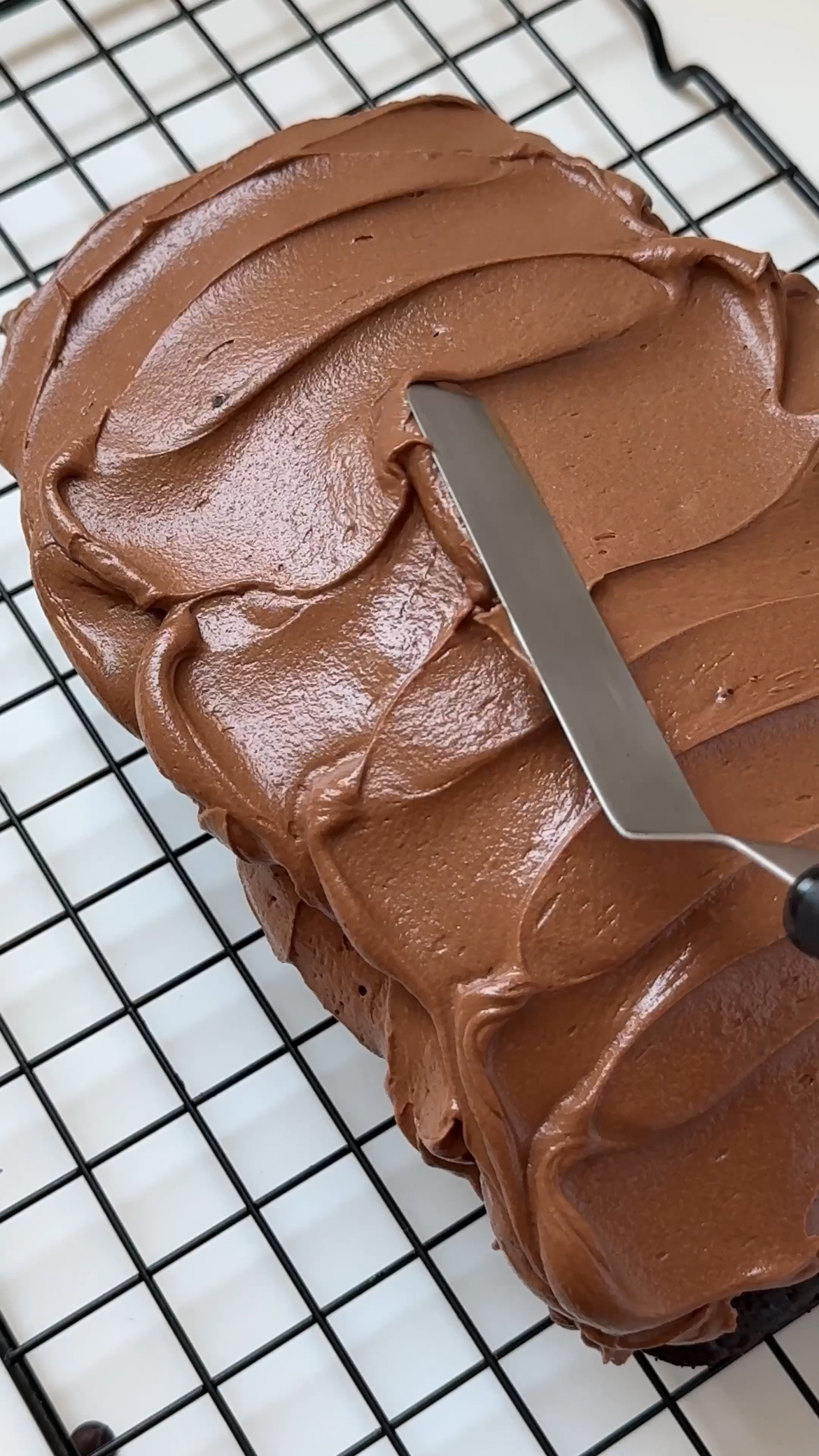 adding chocolate frosting onto the cake