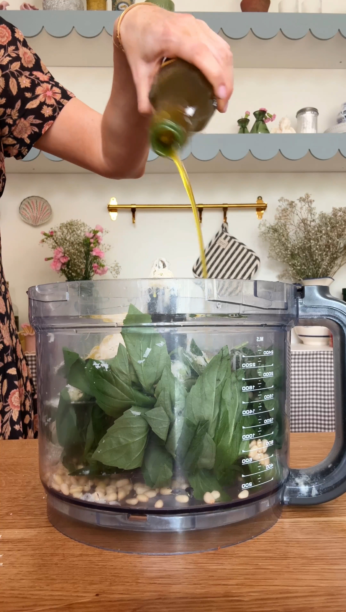 adding olive oil to the food processor for pesto