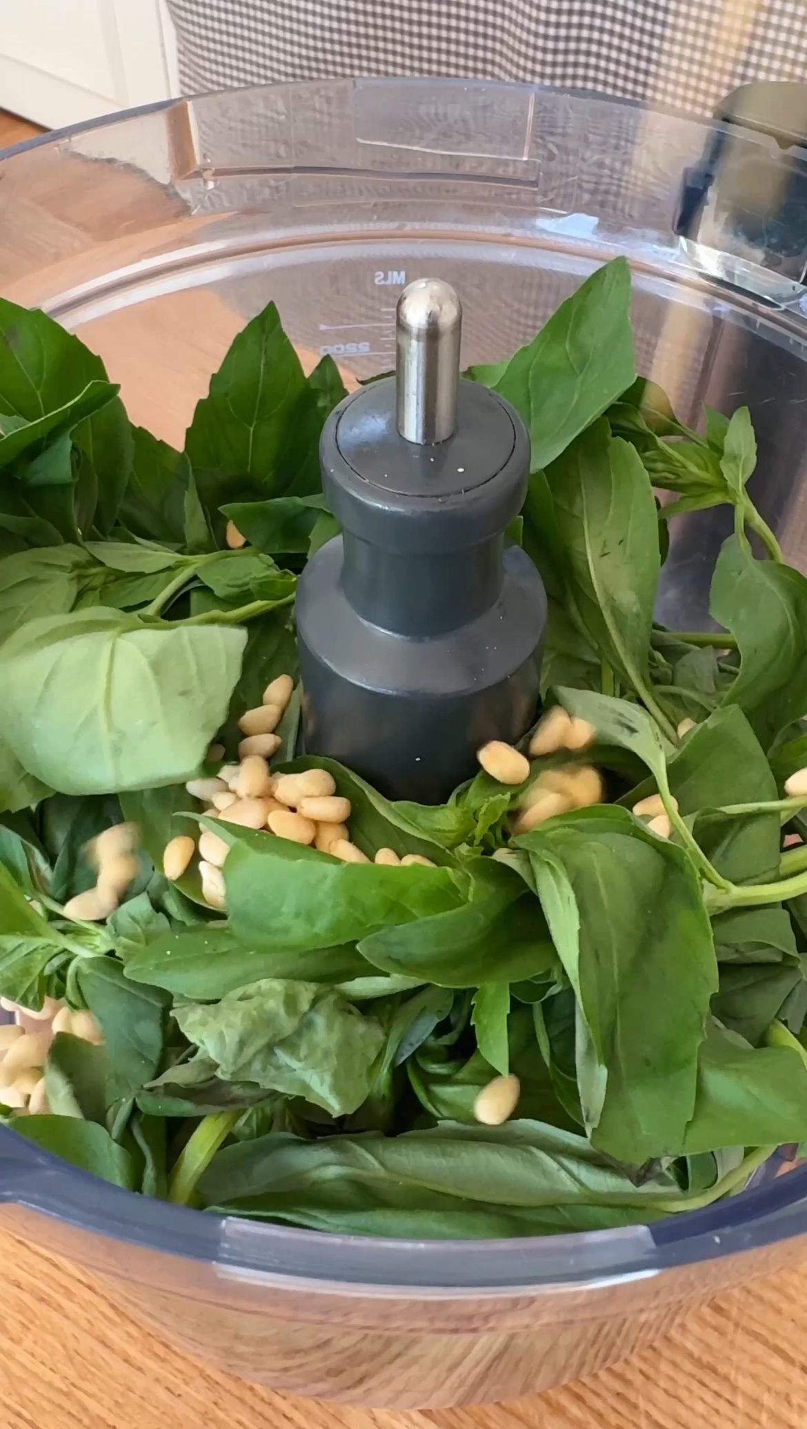 adding pine nuts to the food processor for pesto