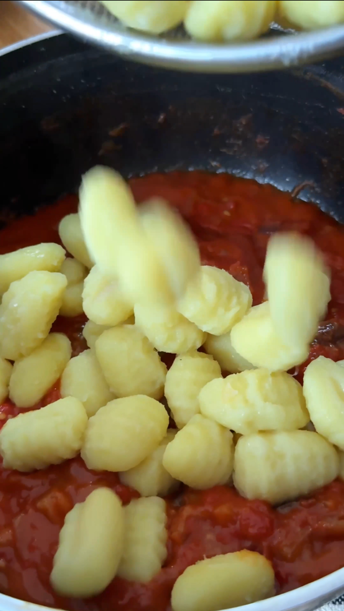 adding gnocchi to tomato sauce