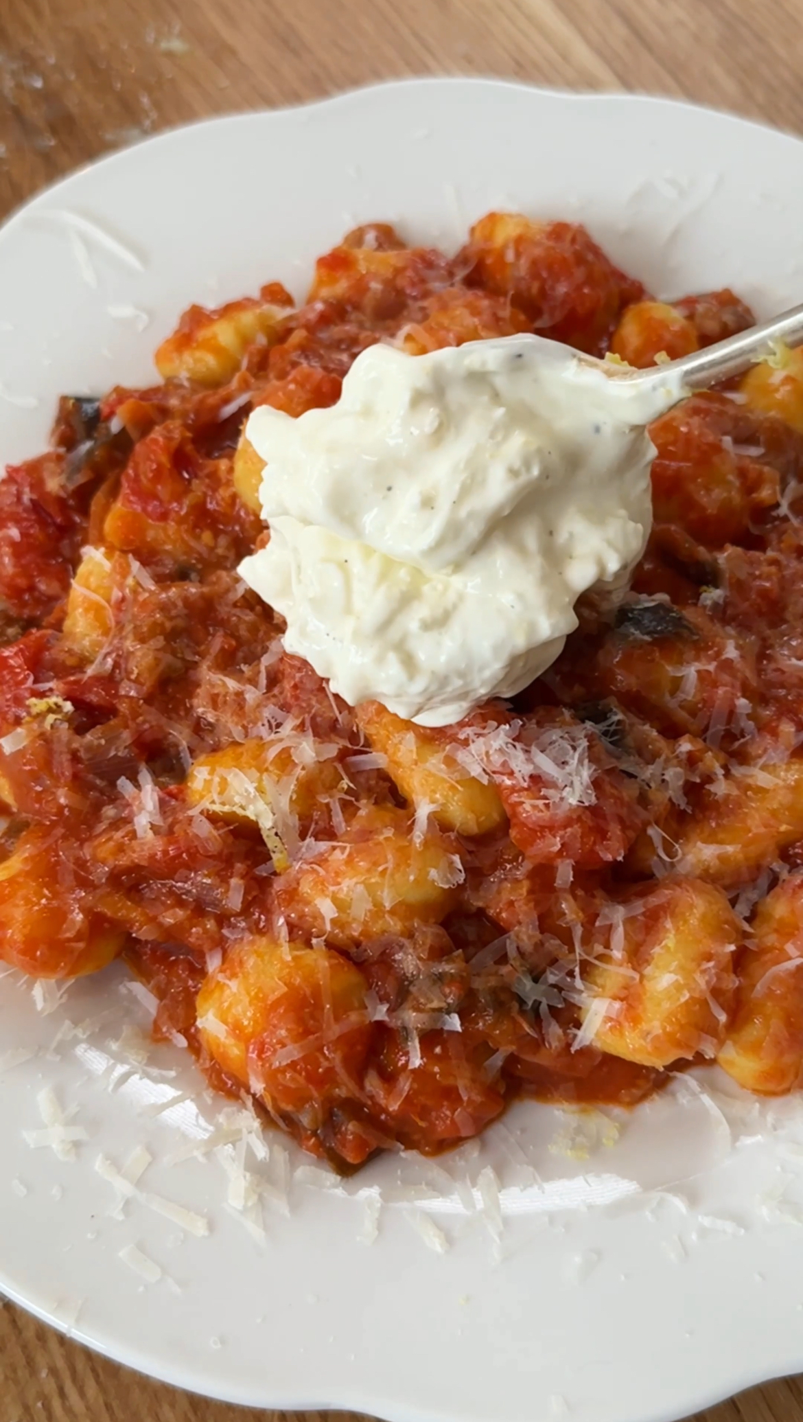 adding creamy topping to gnocchi alla norma