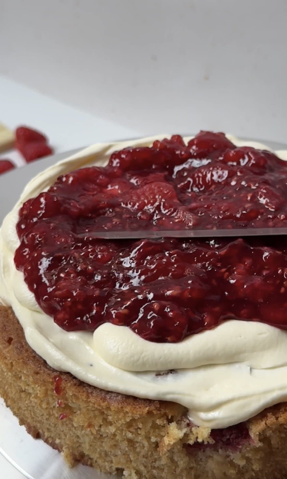 smoothing raspberry jam onto the cake.