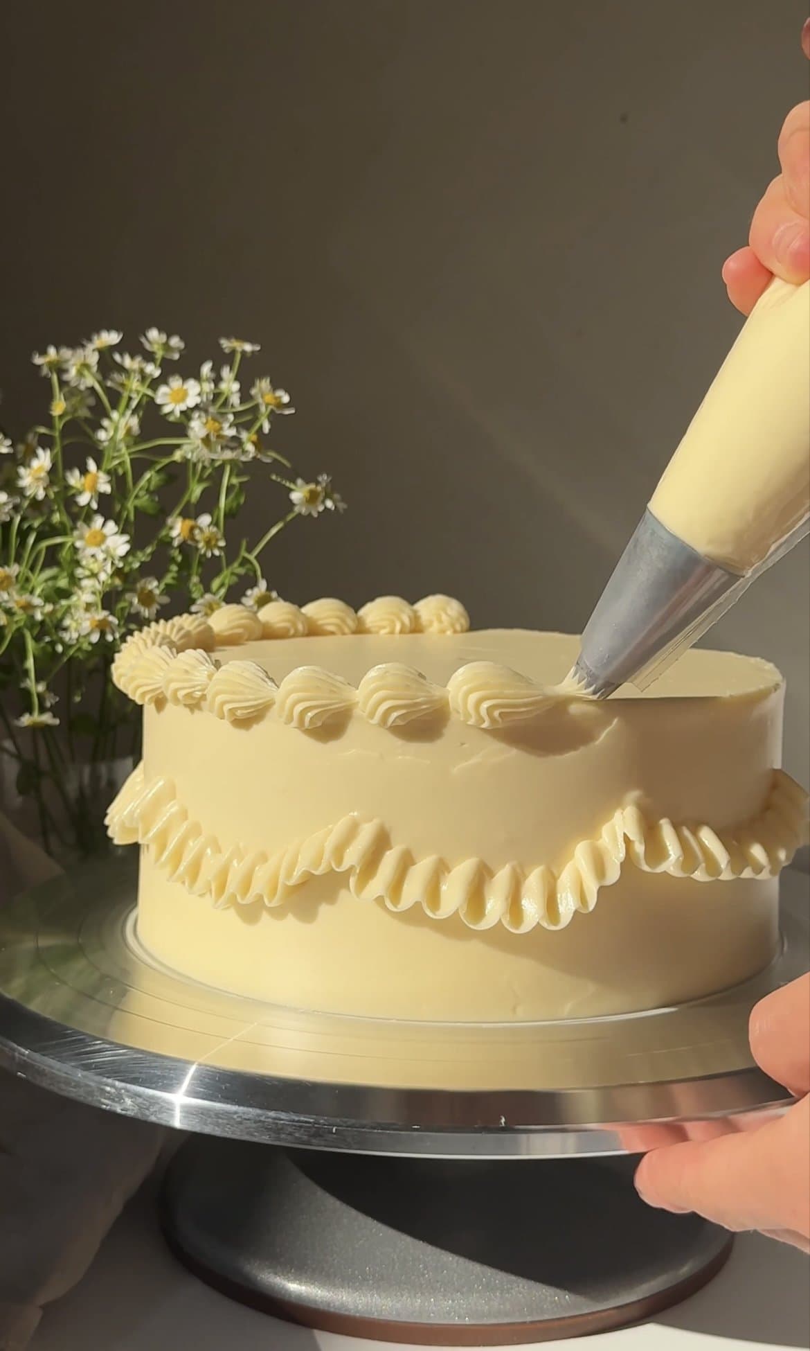 piping the buttercream onto the cake.