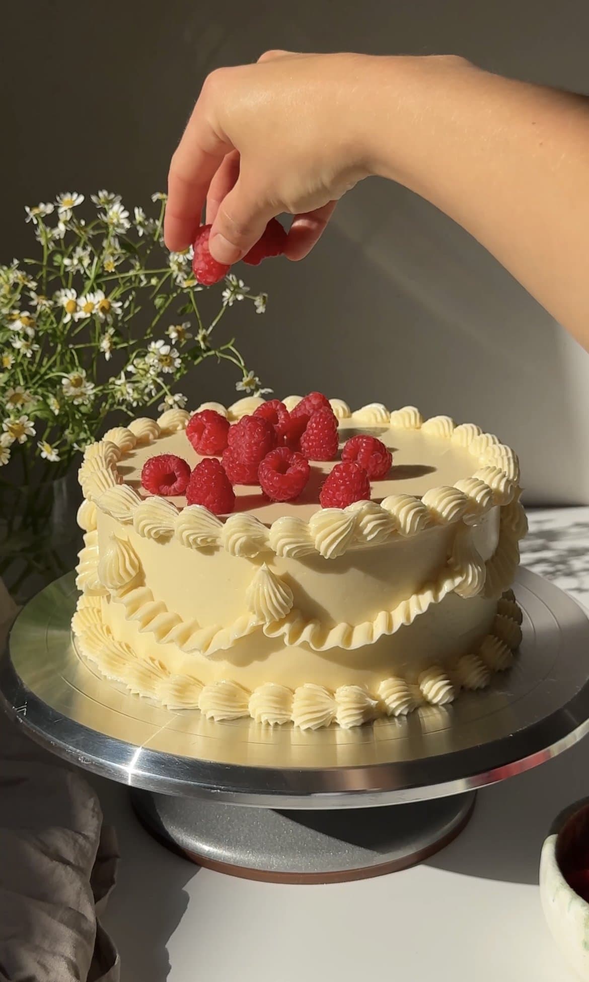 topping the white chocolate raspberry cake with fresh raspberries.