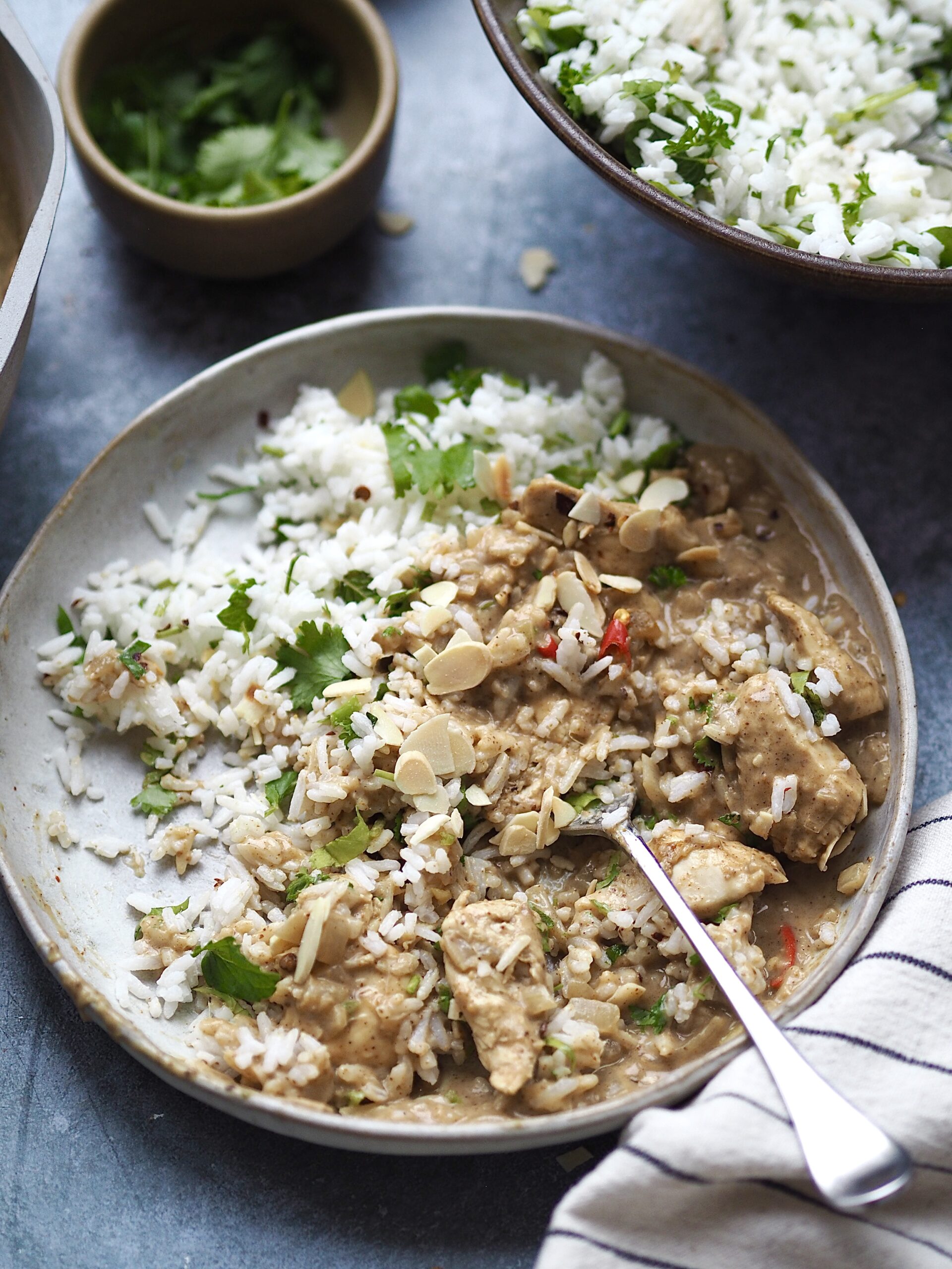 A half eaten plate of almond butter chicken curry and rice.