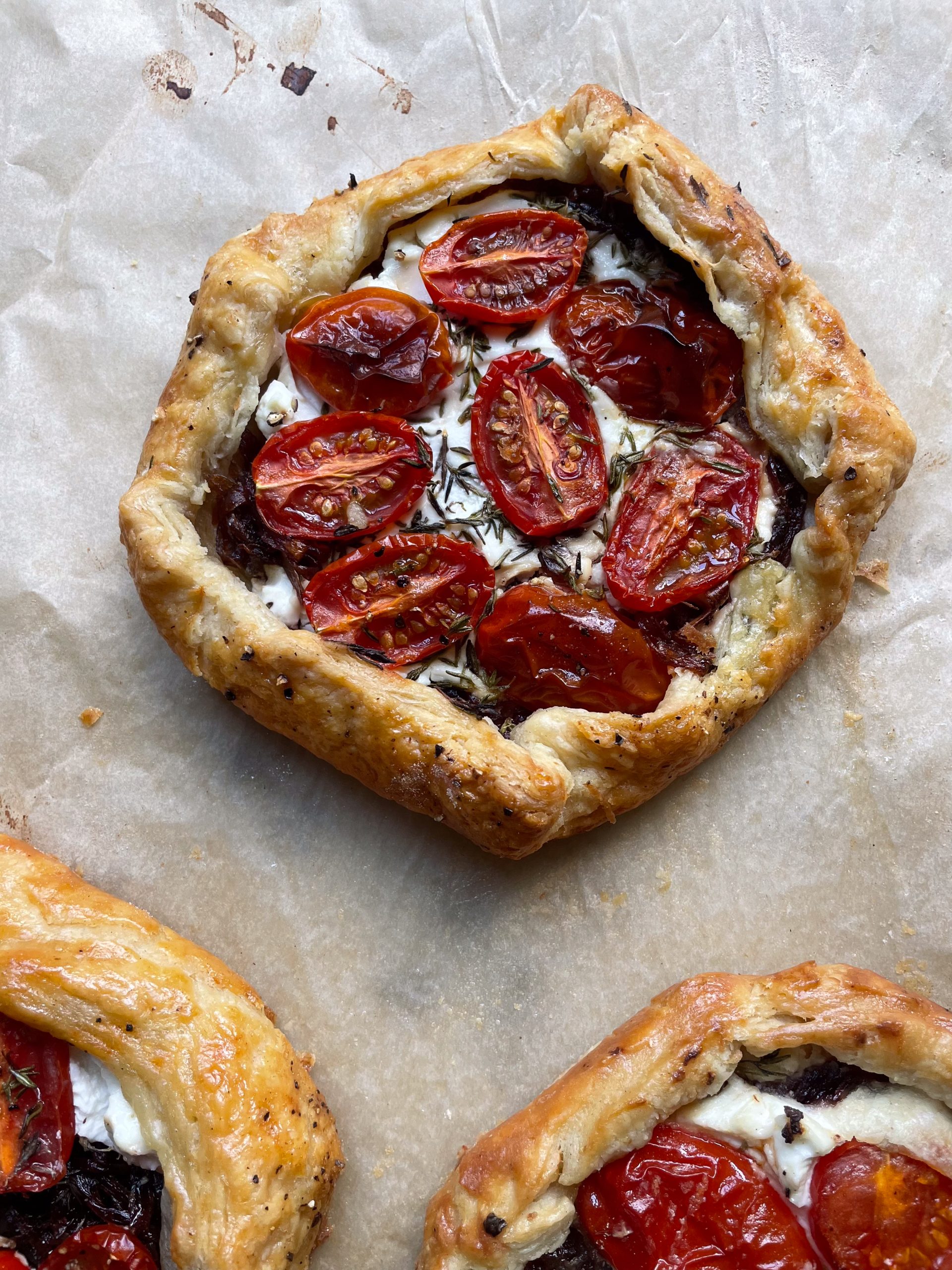 Close up of a caramelised onion galette on a baking parchment lined tray.