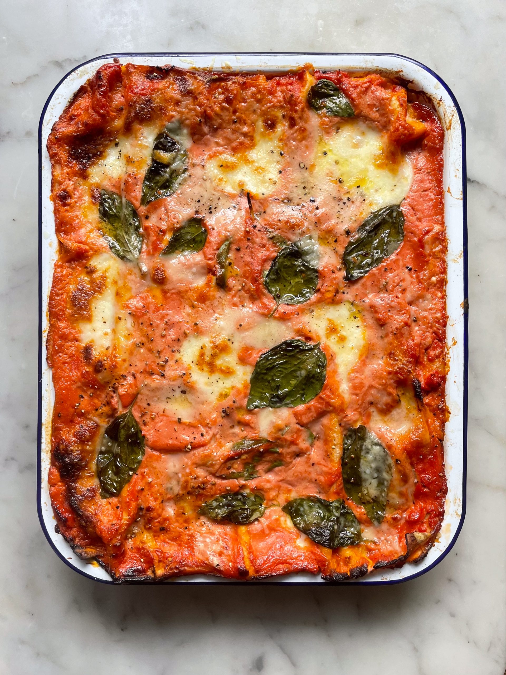 Bake courgette lasagne in a falconware baking dish topped with basil leaves.