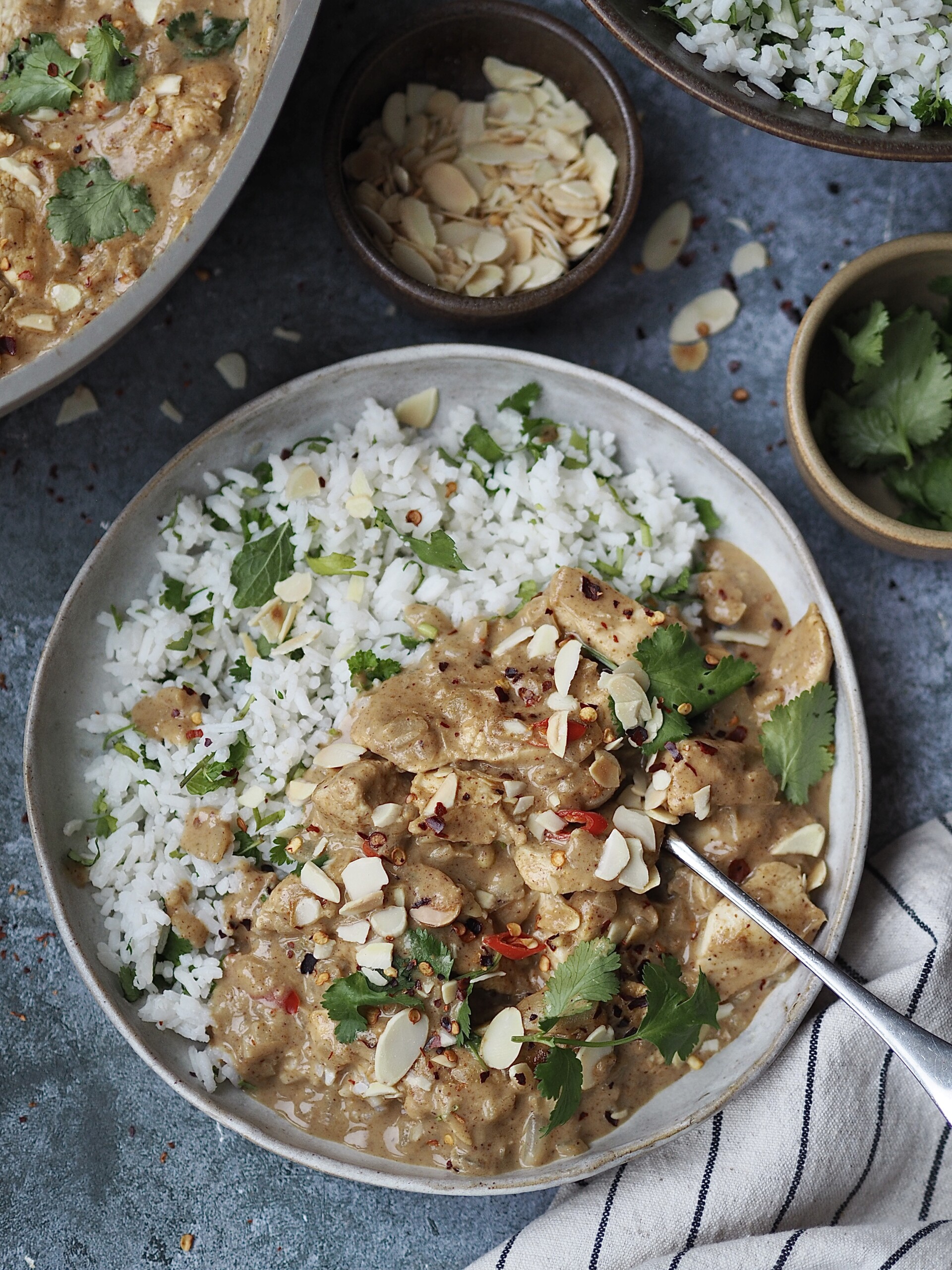 Close up of a plate of chicken curry and rice with a fork in the pile of curry.