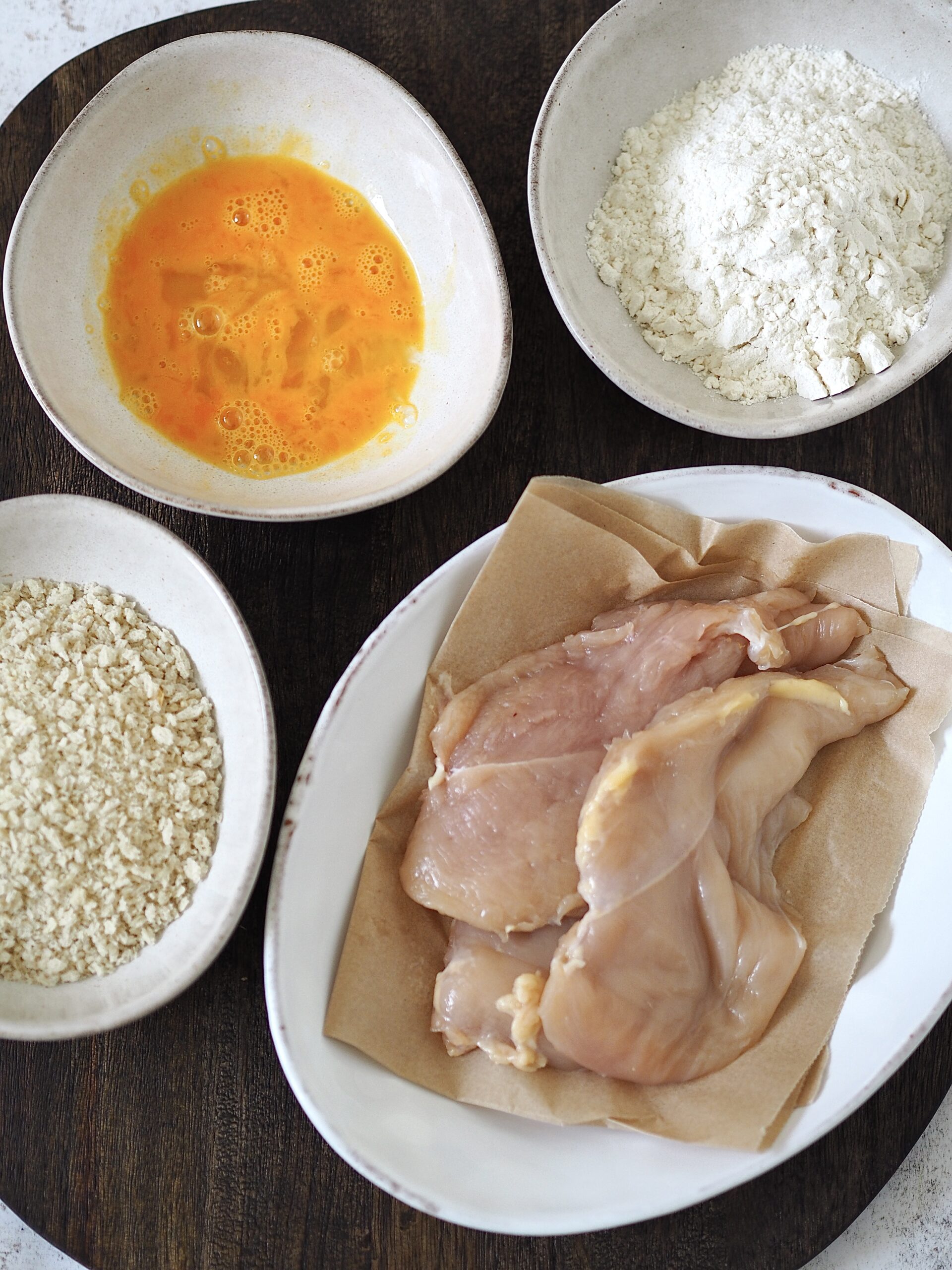 Breading stations set up for chicken cutlets.