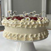 white chocolate raspberry cake on a white cake stand.