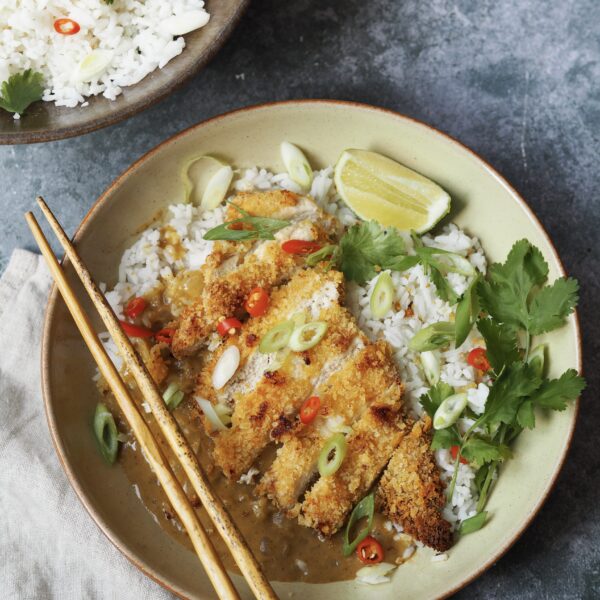 Overhead vew of a chicken katsu and curry sauce rice bowl on a grey stone background.