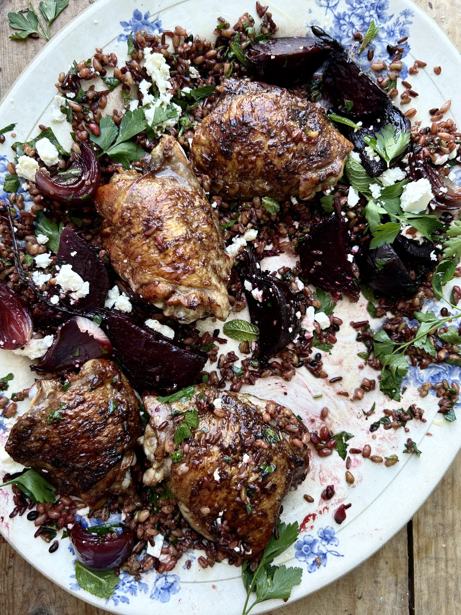 Quarter eaten platted of chicken with beetroot, red onion and mixed grains. 