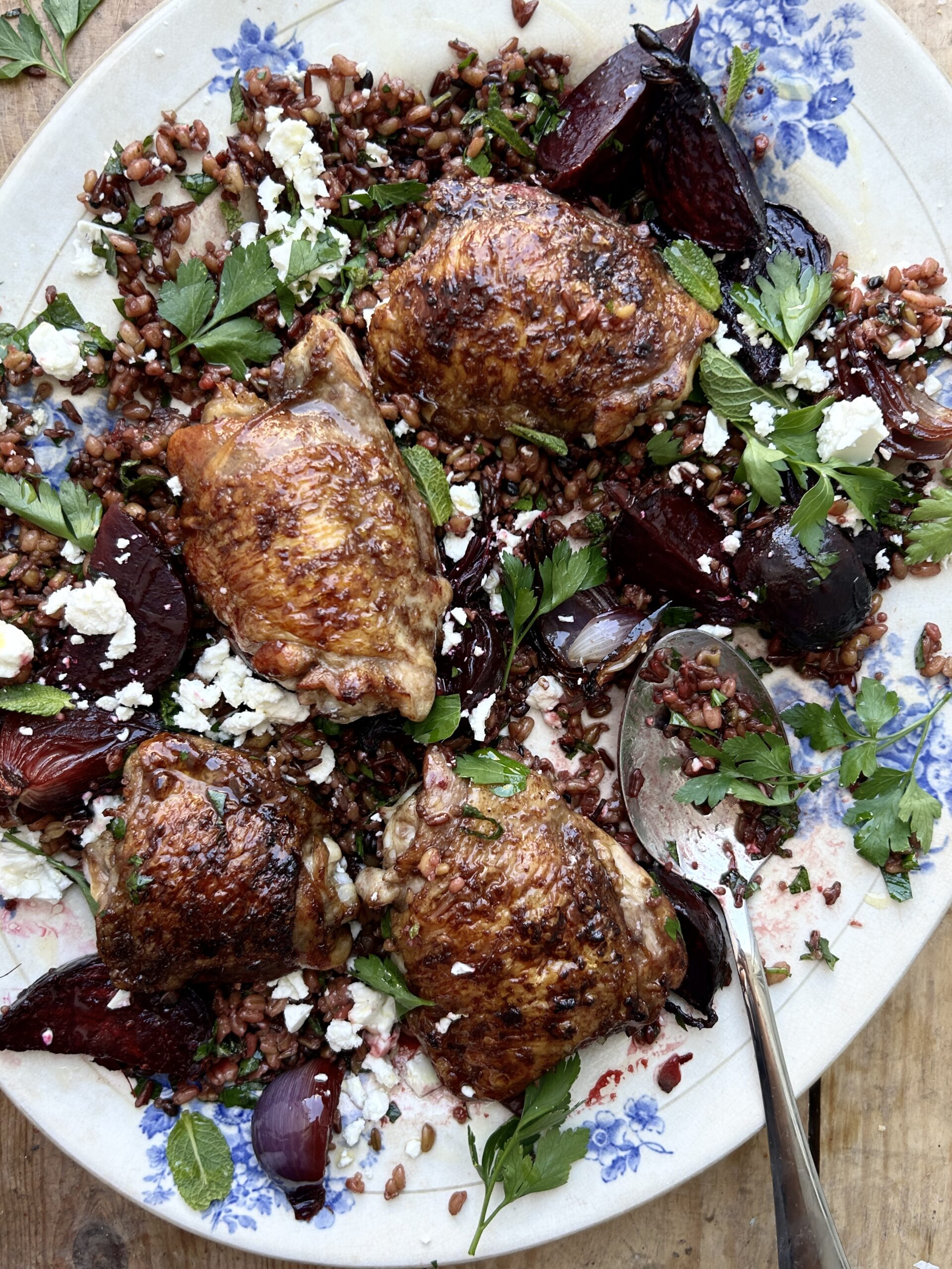 Close up of chicken thighs and beetroot with a feta and herb garnish.