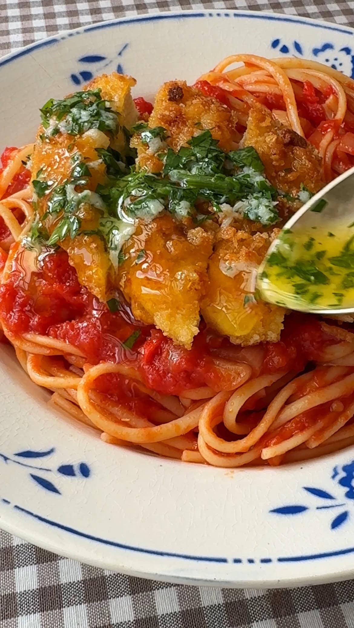 spooning garlic butter over the chicken parnesan garlic pasta.