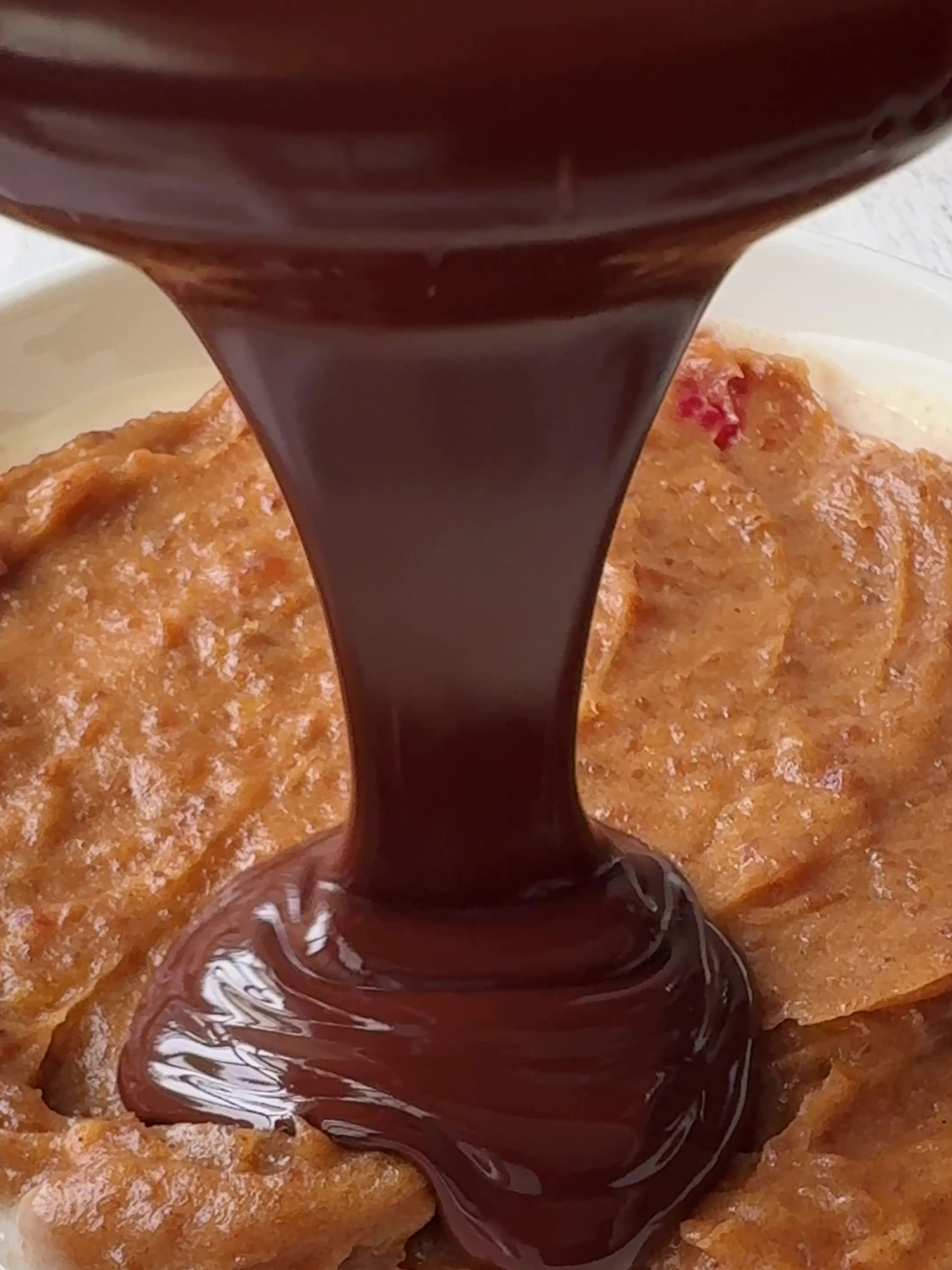 Pouring melted chocolate over date caramel 