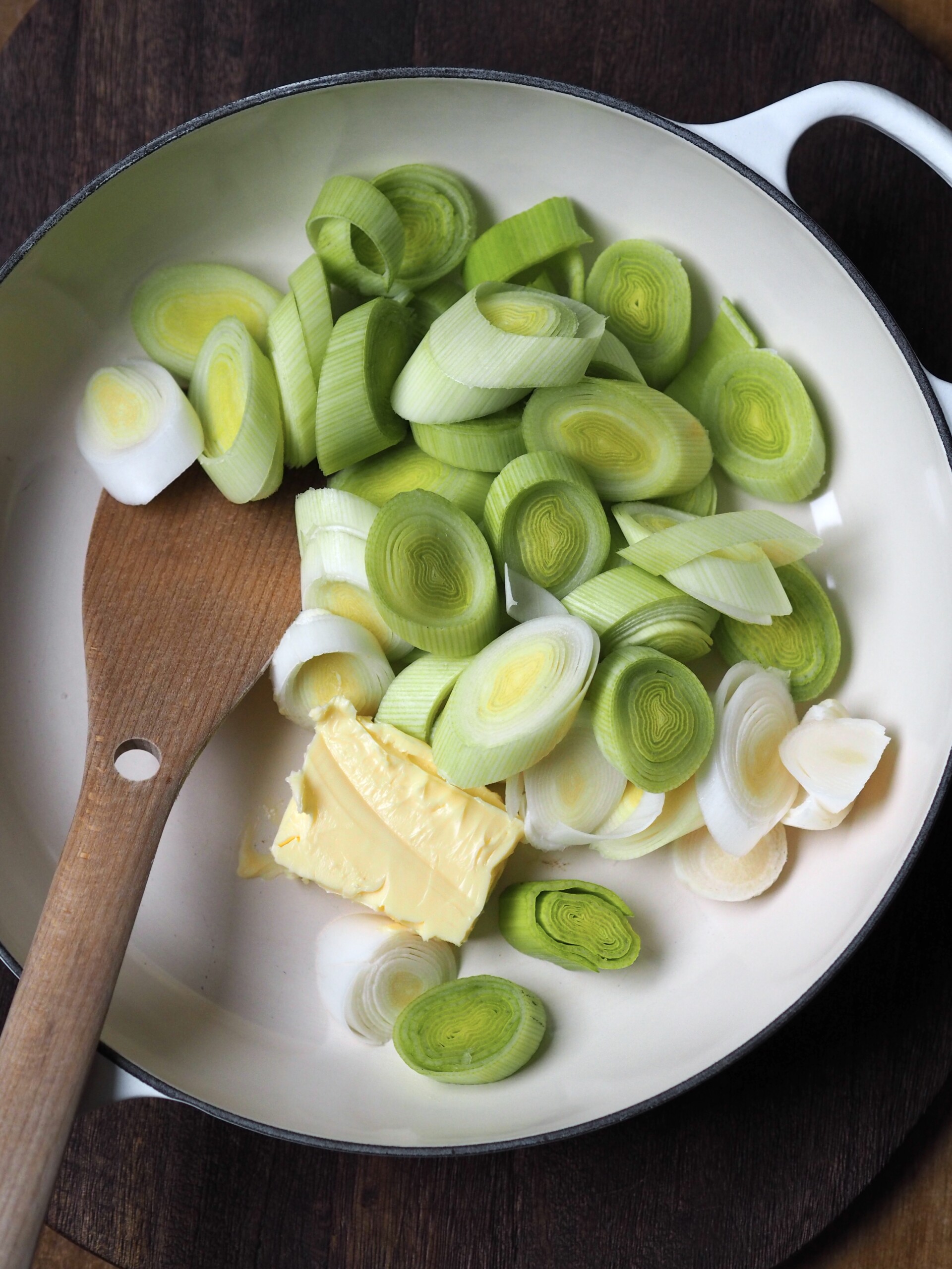 Leeks being fried with butter in a shallow casserole.