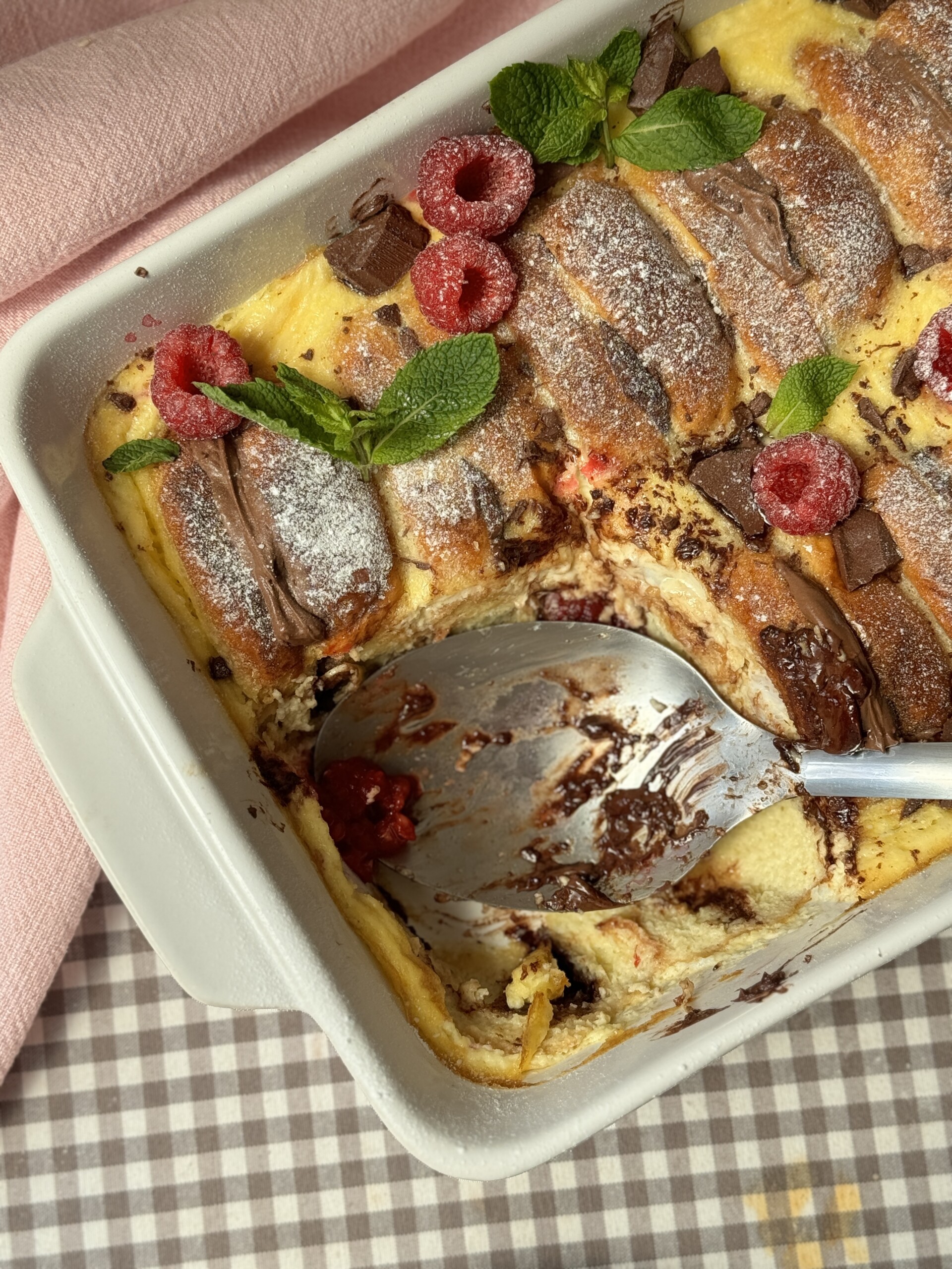 spoon out of brioche pudding in the tin