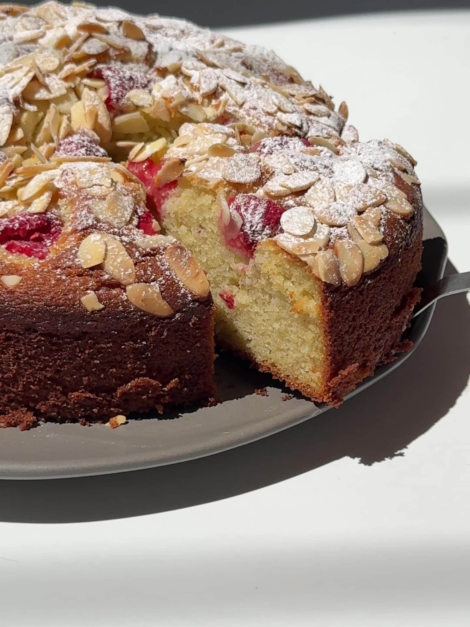 Raspberry, Almond and Ricotta Cake on a plate sliced.