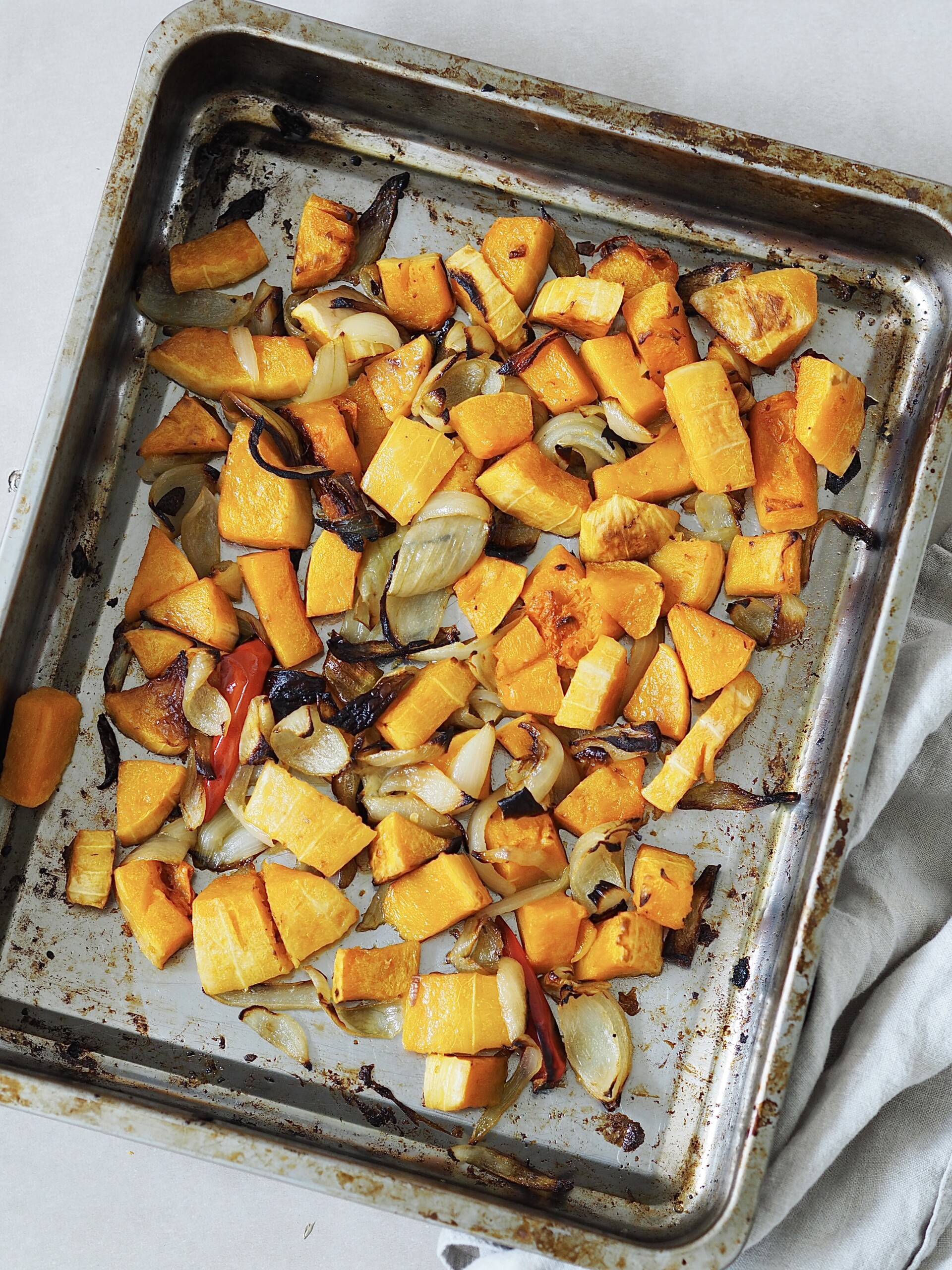 Roasted vegetables for squash soup on a metal roasting tray.