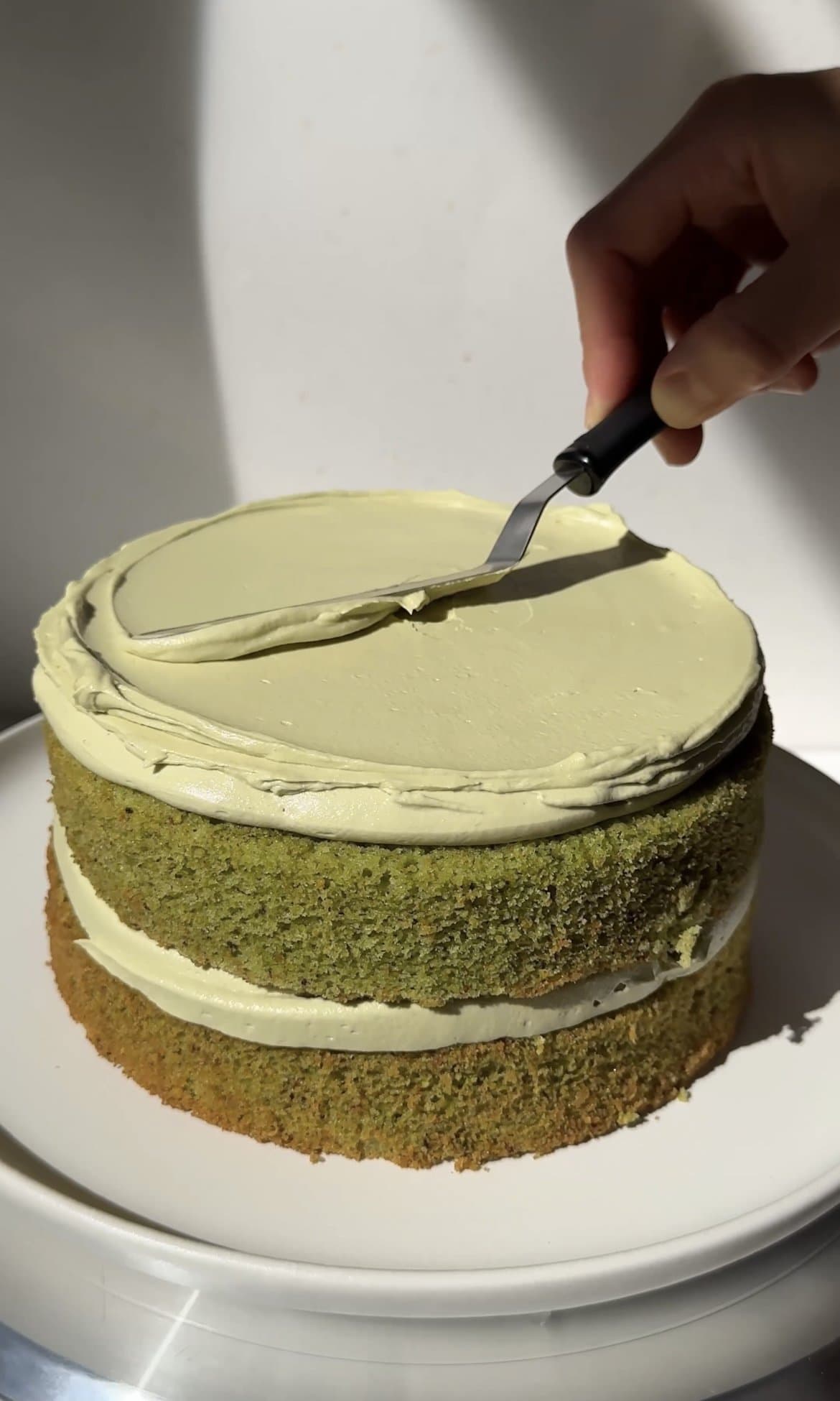 smoothing pistachio icing onto the cake.