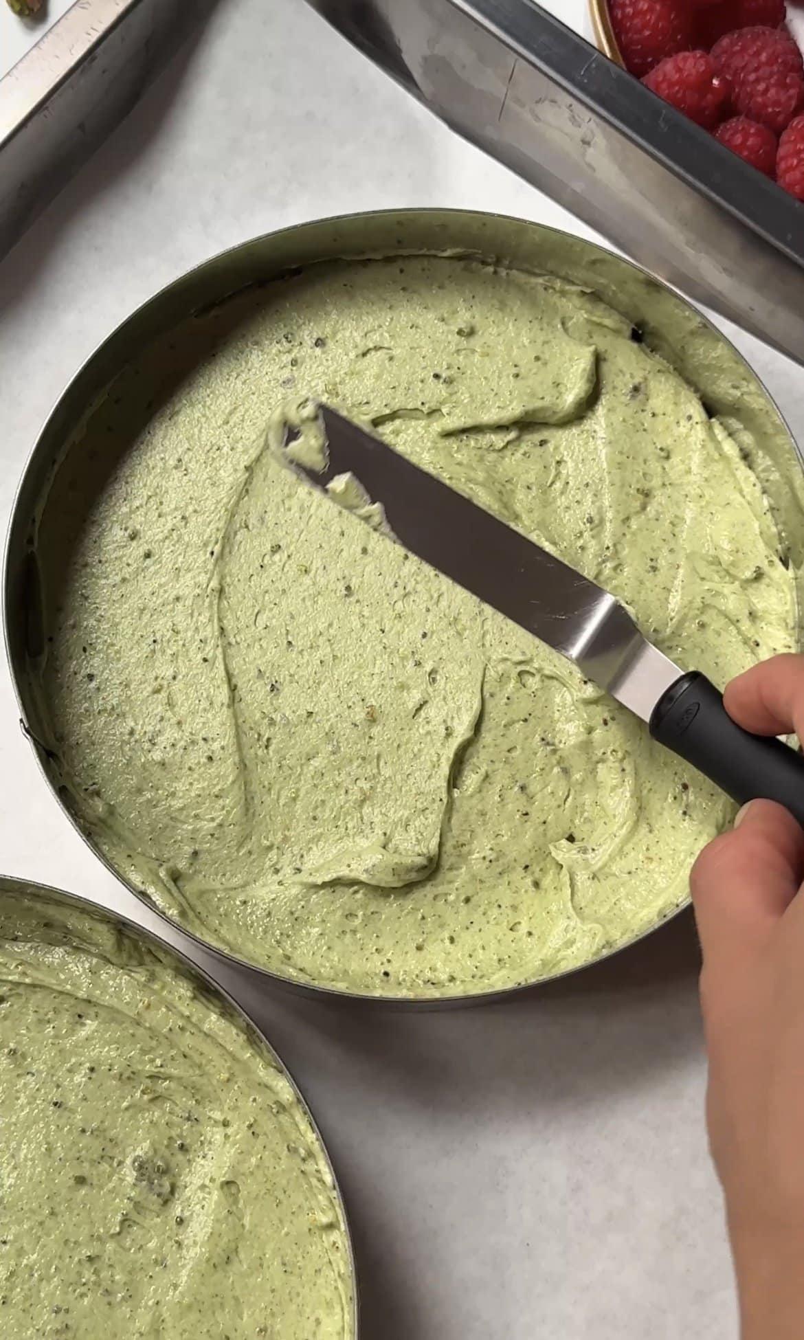 smoothing pistachio cake batter into tins.