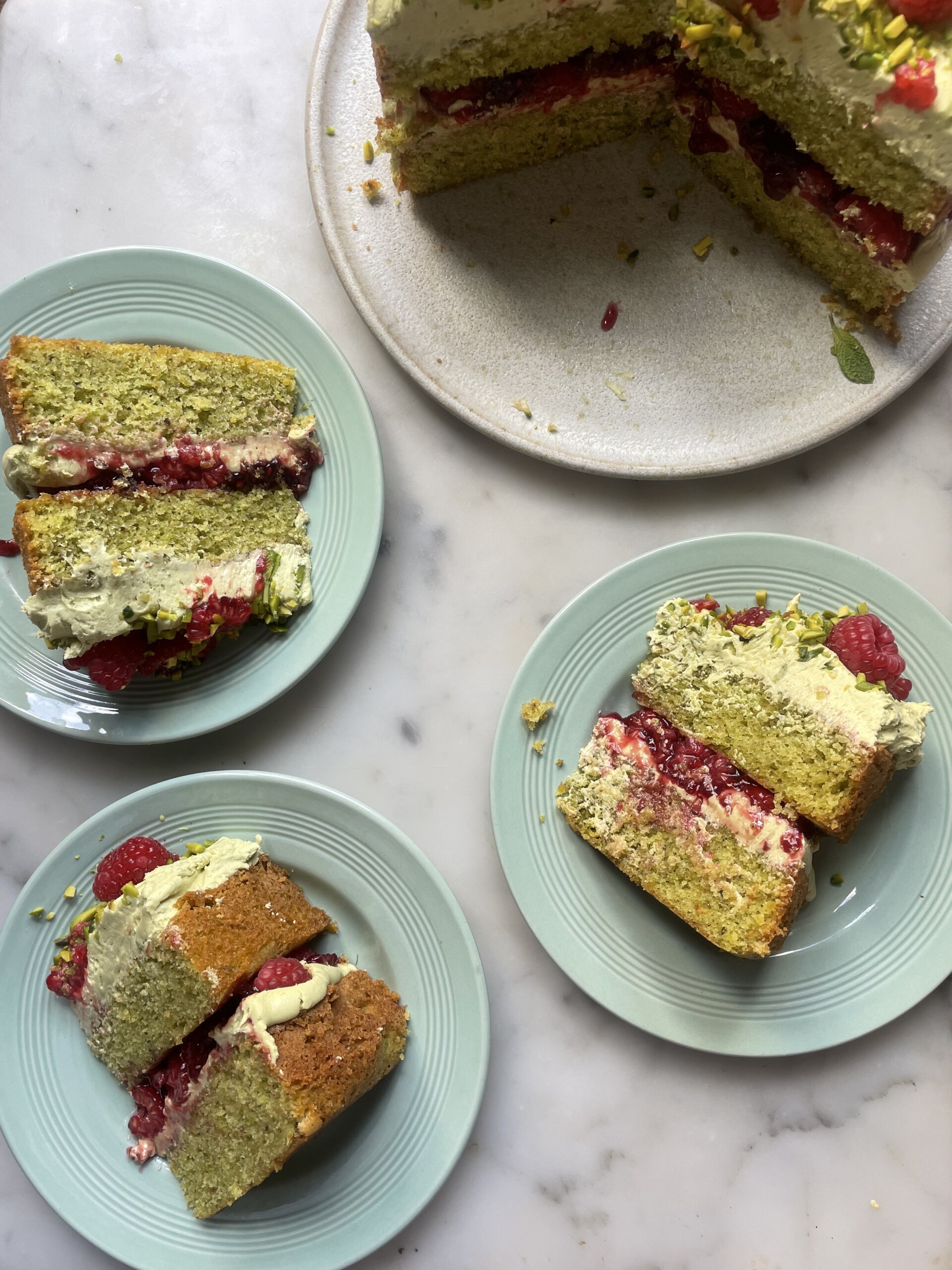 slices of pistachio raspberry cake on blue plates