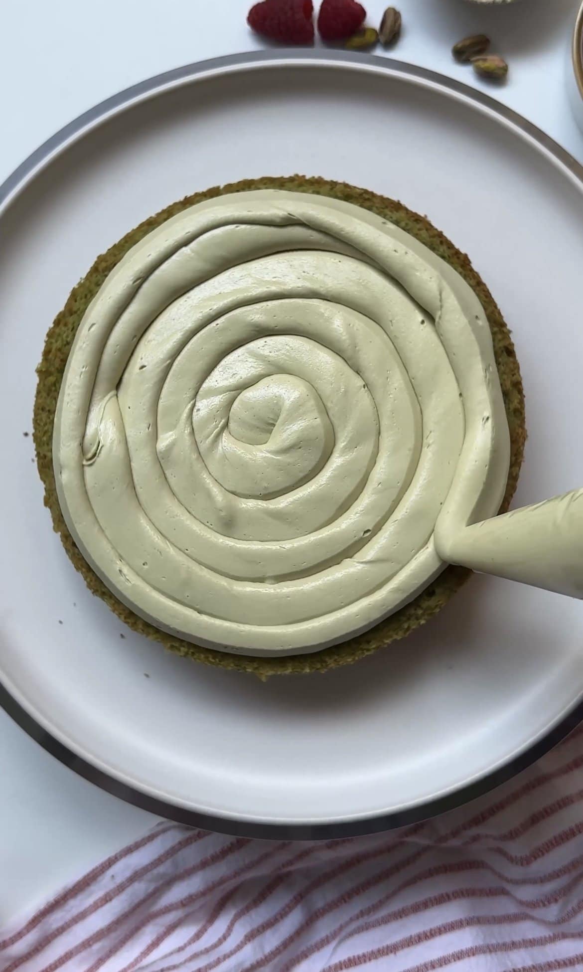 piping icing onto the pistachio sponge.