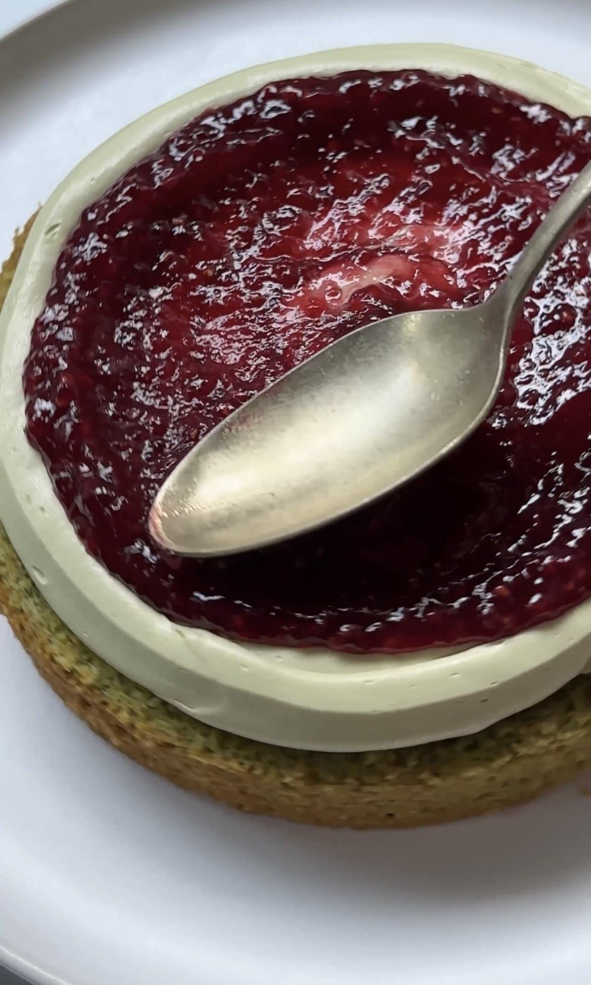 adding raspberry jam to the cake layers.