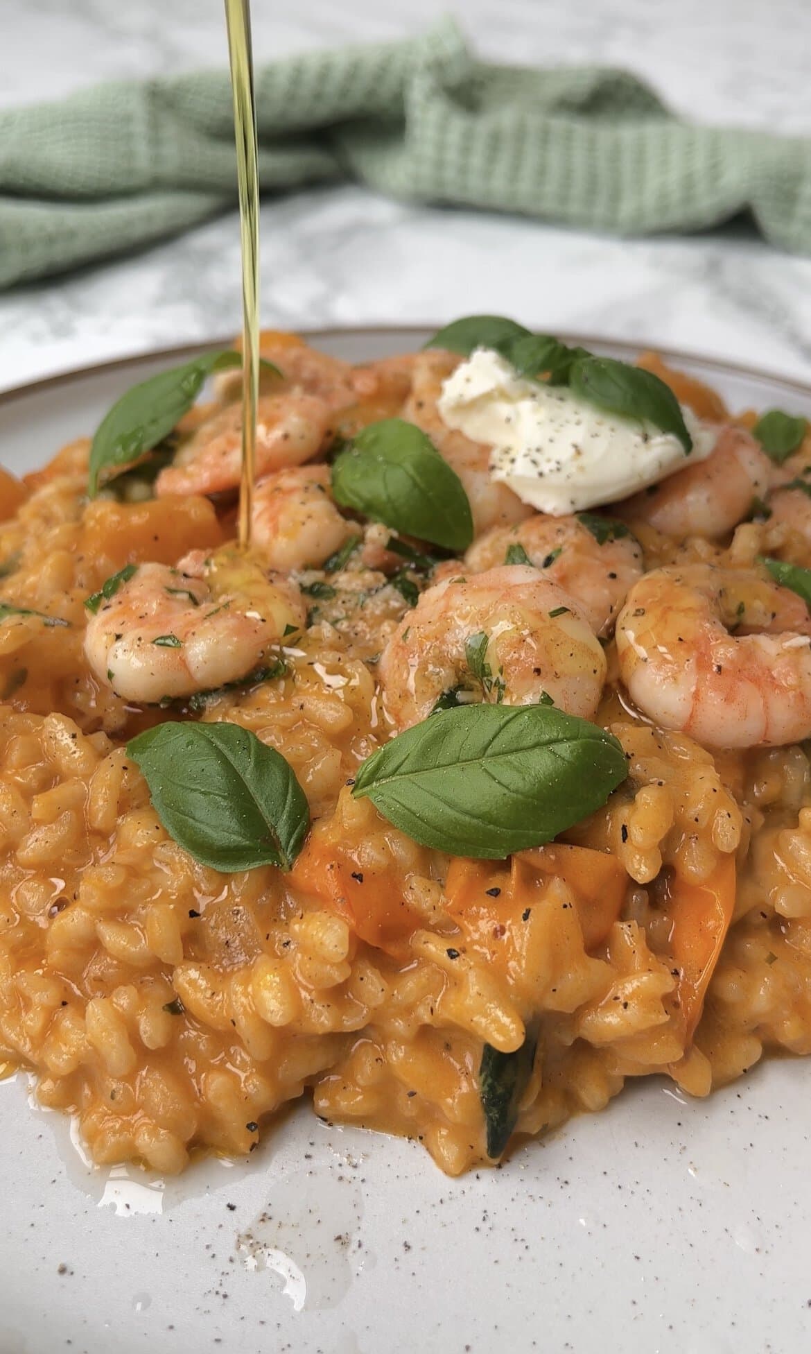 tomato mascarpone risotto on a plate plate, drizzling over olive oil.