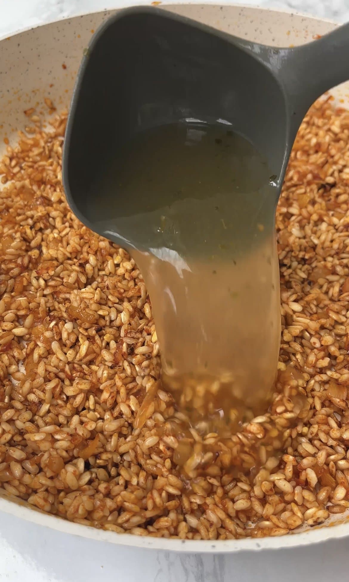 adding stock to risotto rice.