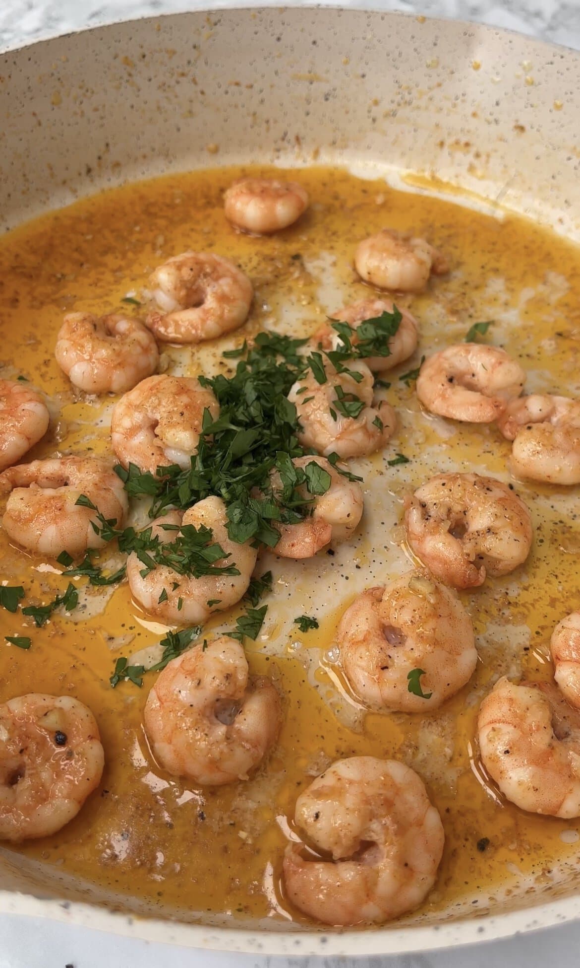 adding parsley to garlic prawns