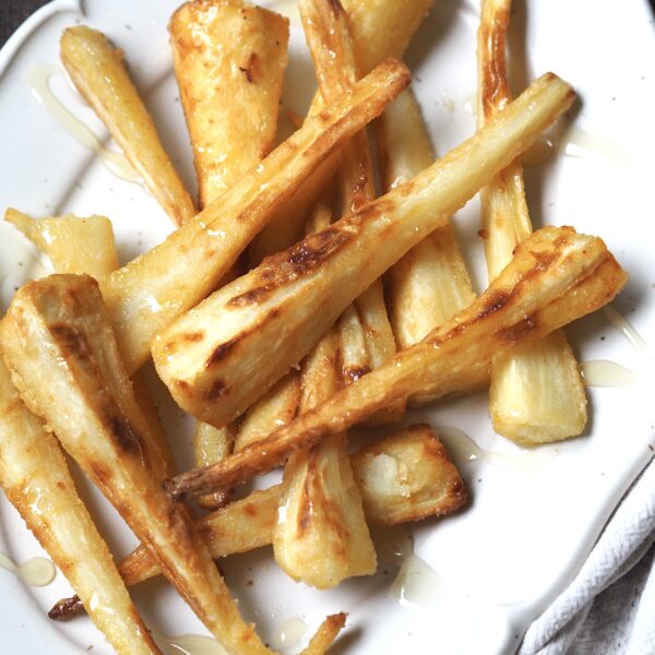 Honey glazed parsnips close up on a white serving platter.