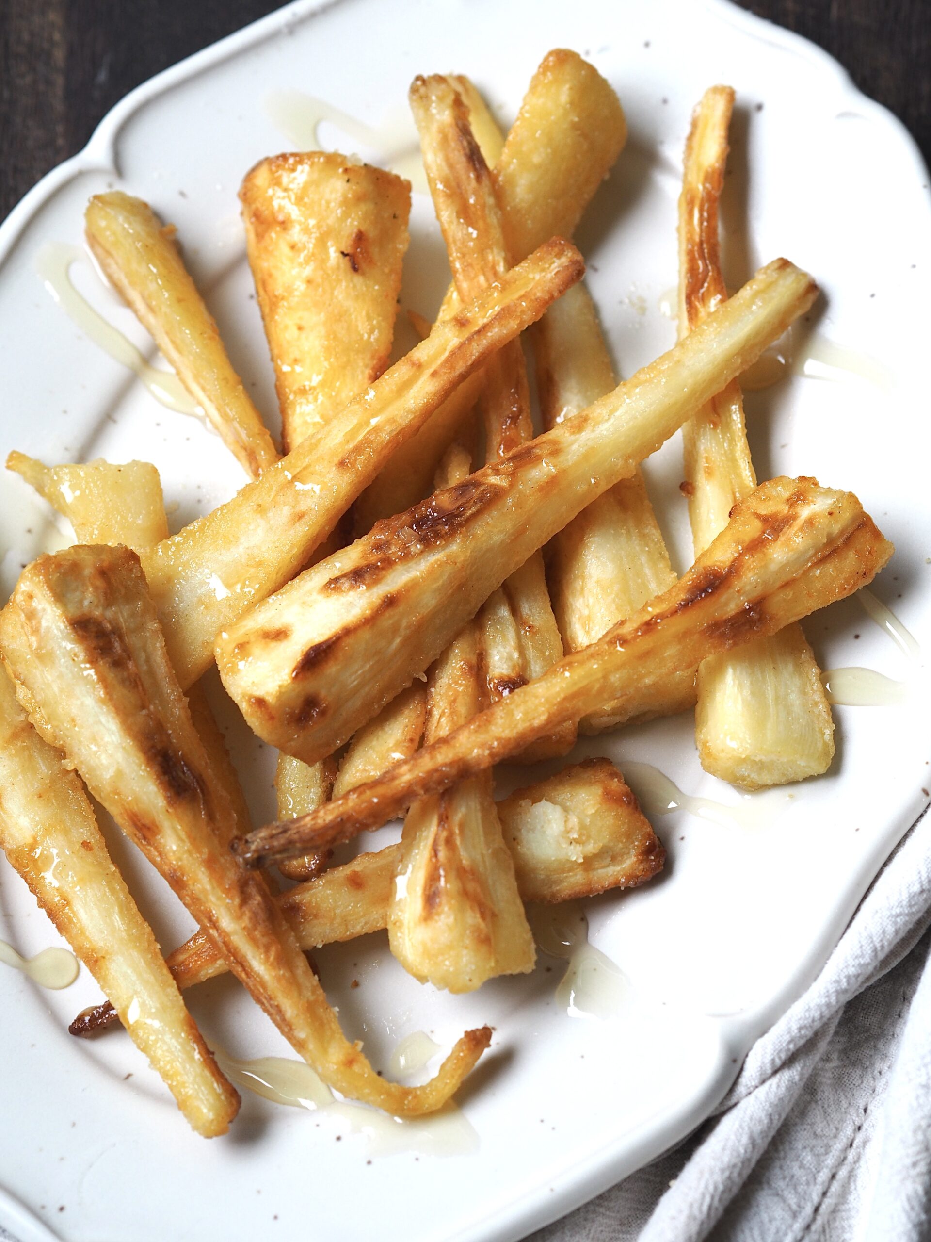 Honey glazed parsnips close up on a white serving platter.