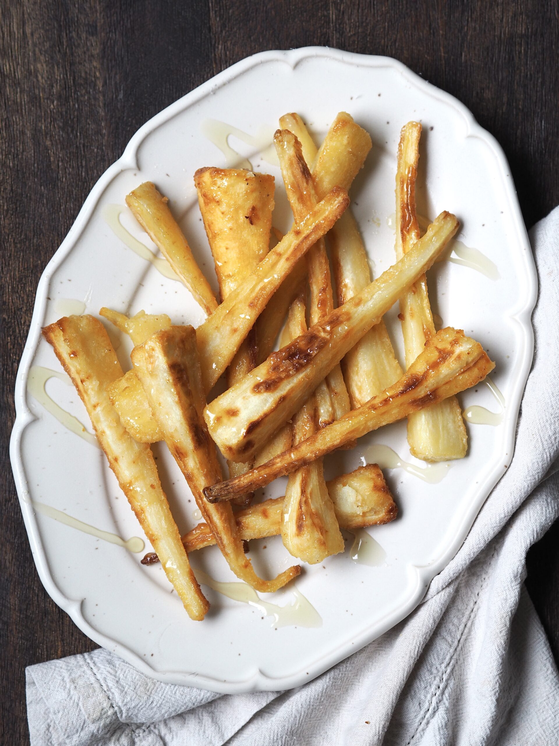 White serving platter of roasted parsnips.