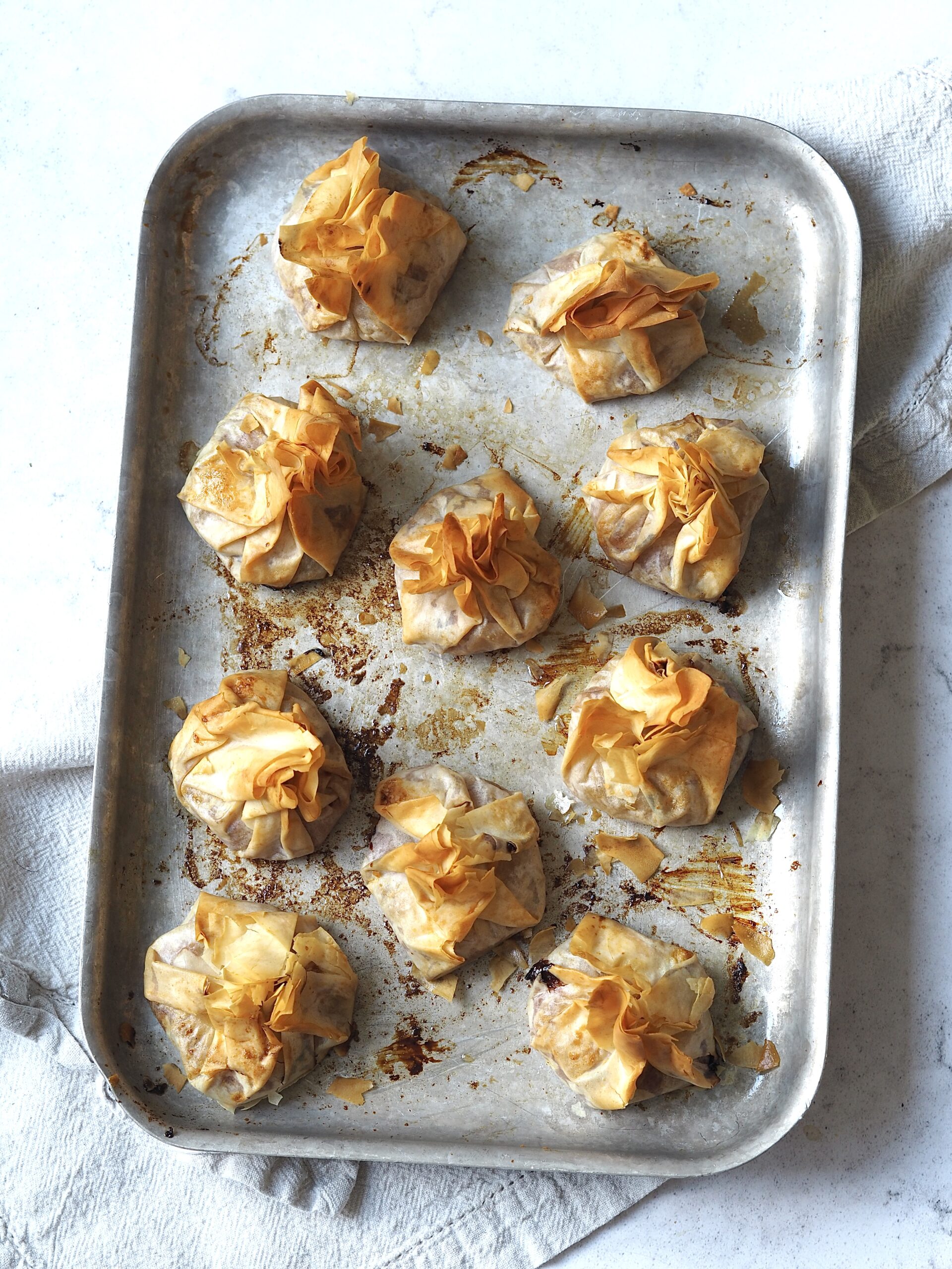 Baked cranberry sauce and brie filo parcels on a metal baking tray.