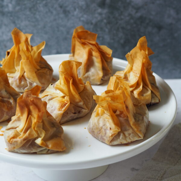 White serving platter of filo pastry parcels.