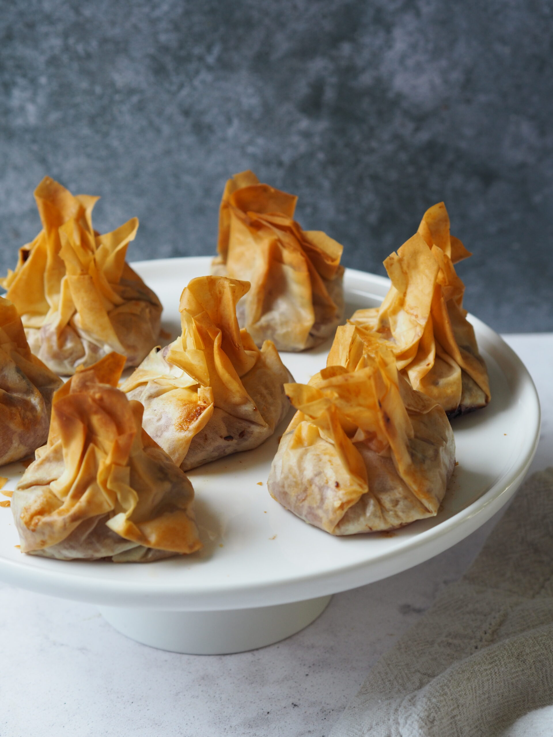 White serving platter of filo pastry parcels. 