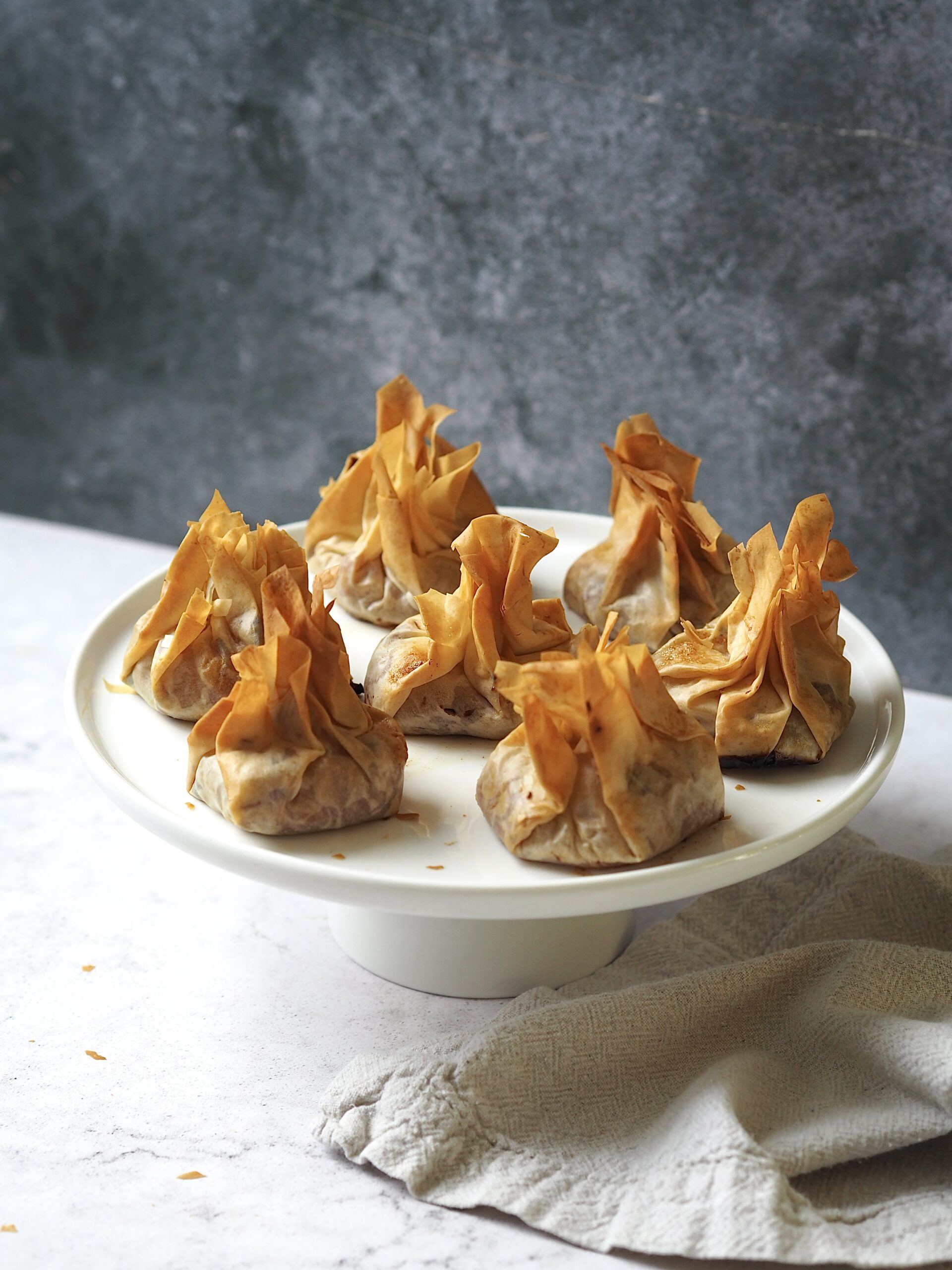 White cake stand of brie and cranberry parcels. 