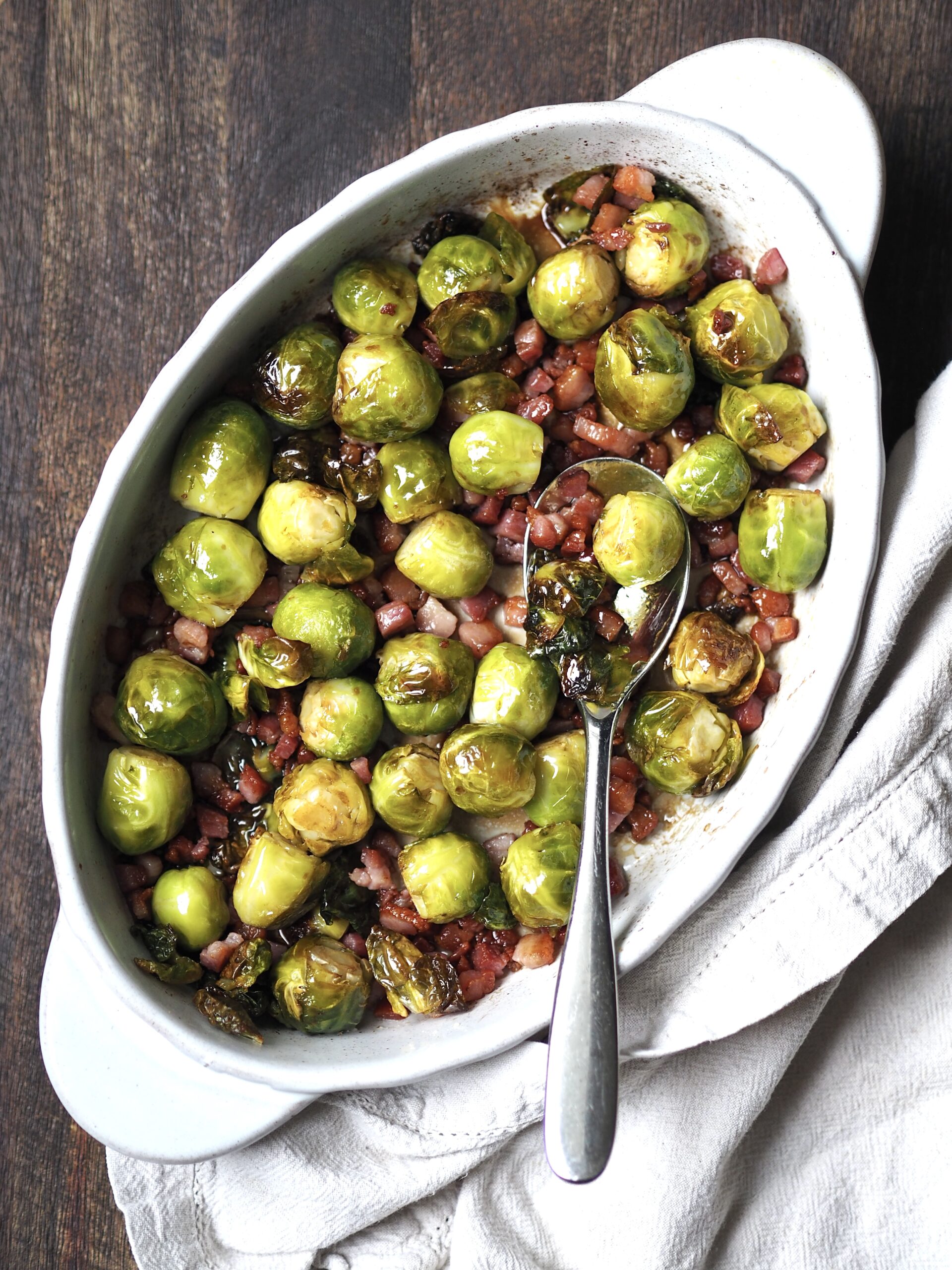 White serving dish of honey bacon balsamic roasted brussels sprouts. 