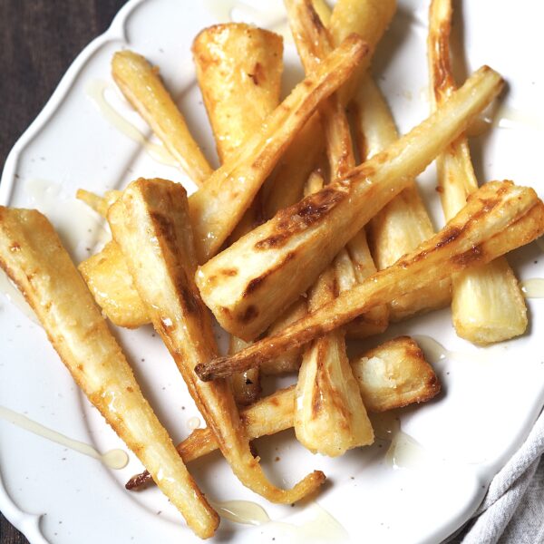 White platter of roasted parsnips drizzled with honey.