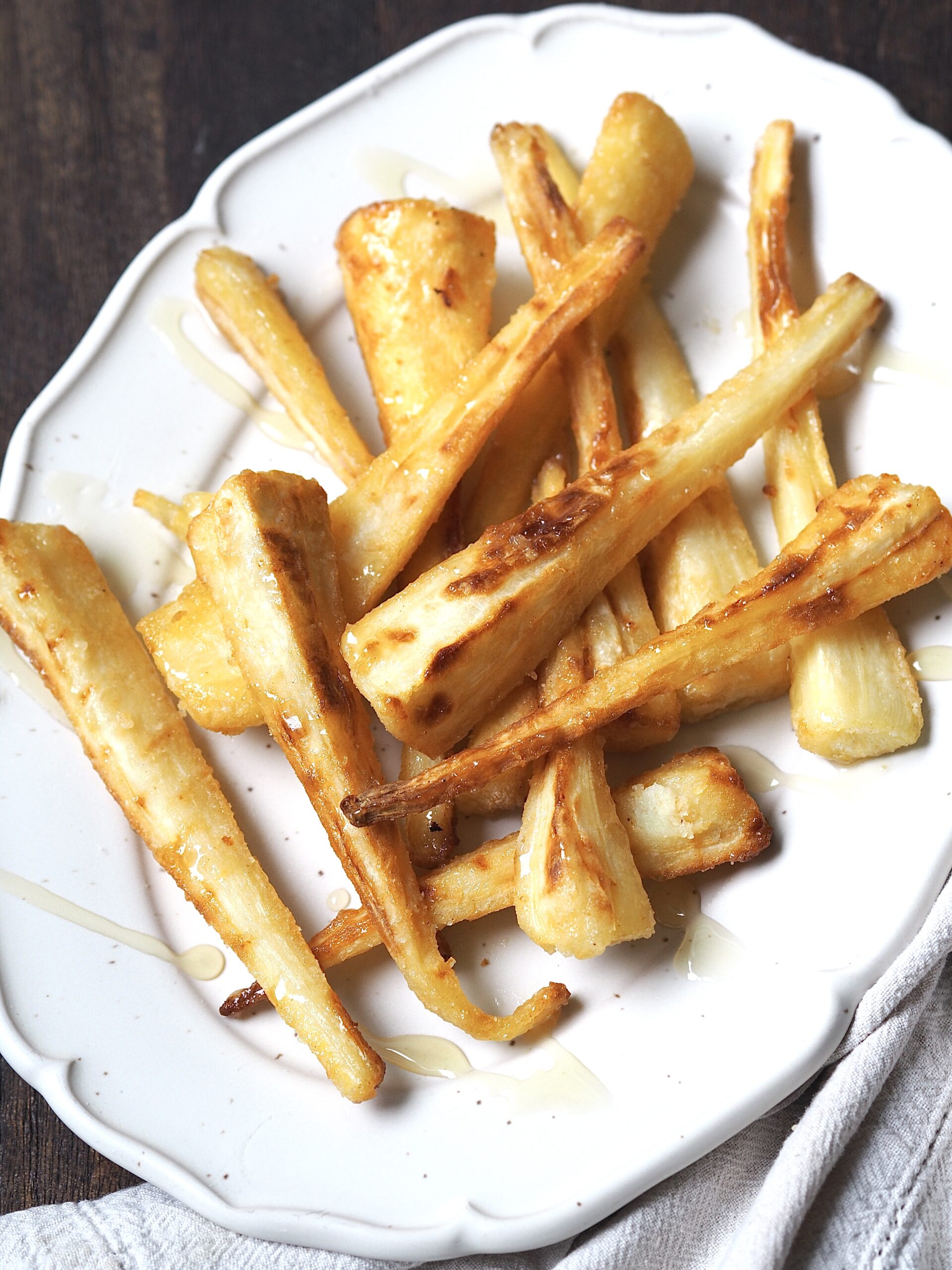 White platter of roasted parsnips drizzled with honey.